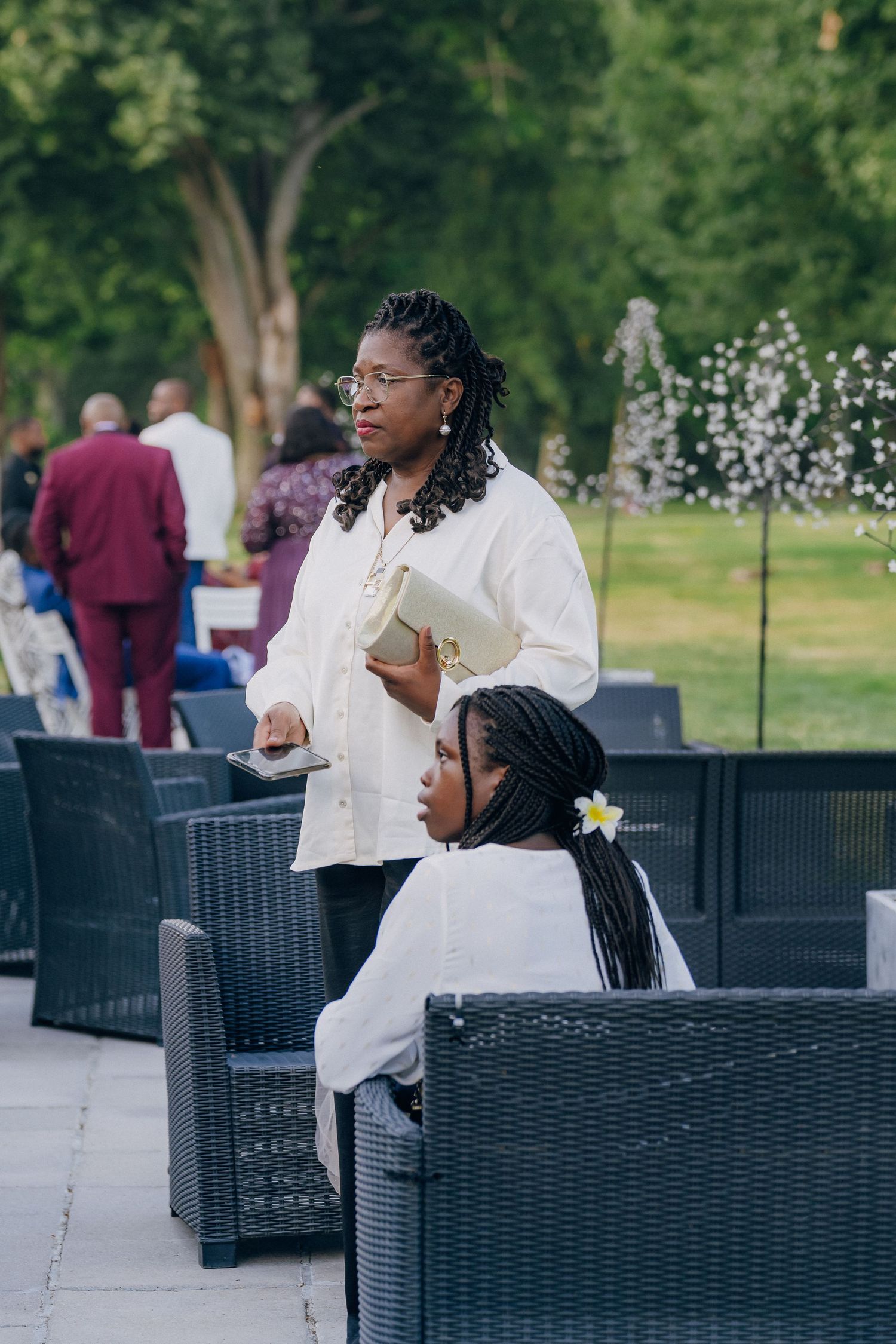 Two guests in white attire relaxing on outdoor patio furniture during a wedding event.