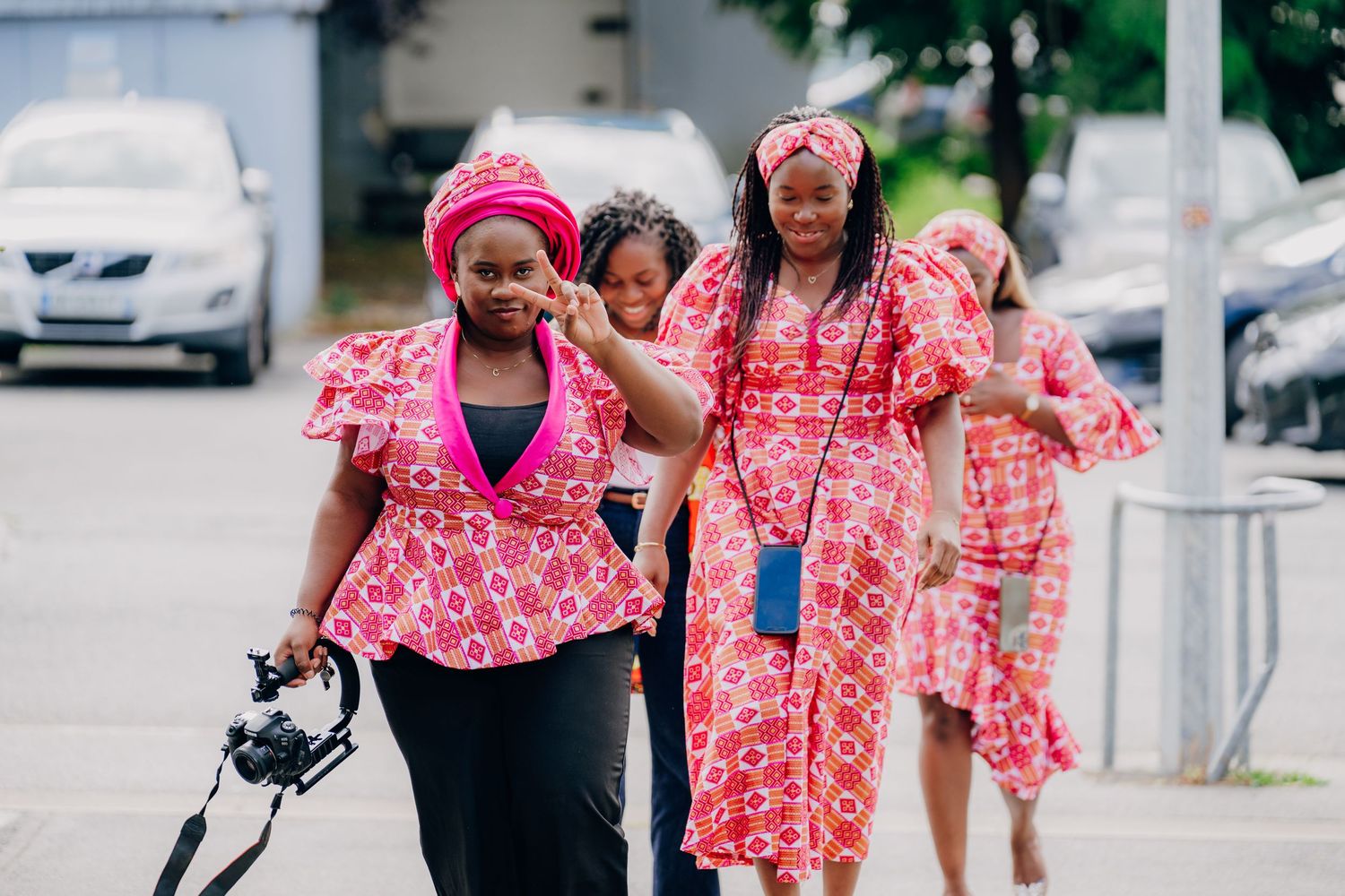 Group wearing matching pink and red patterned outfits walking together outdoors.