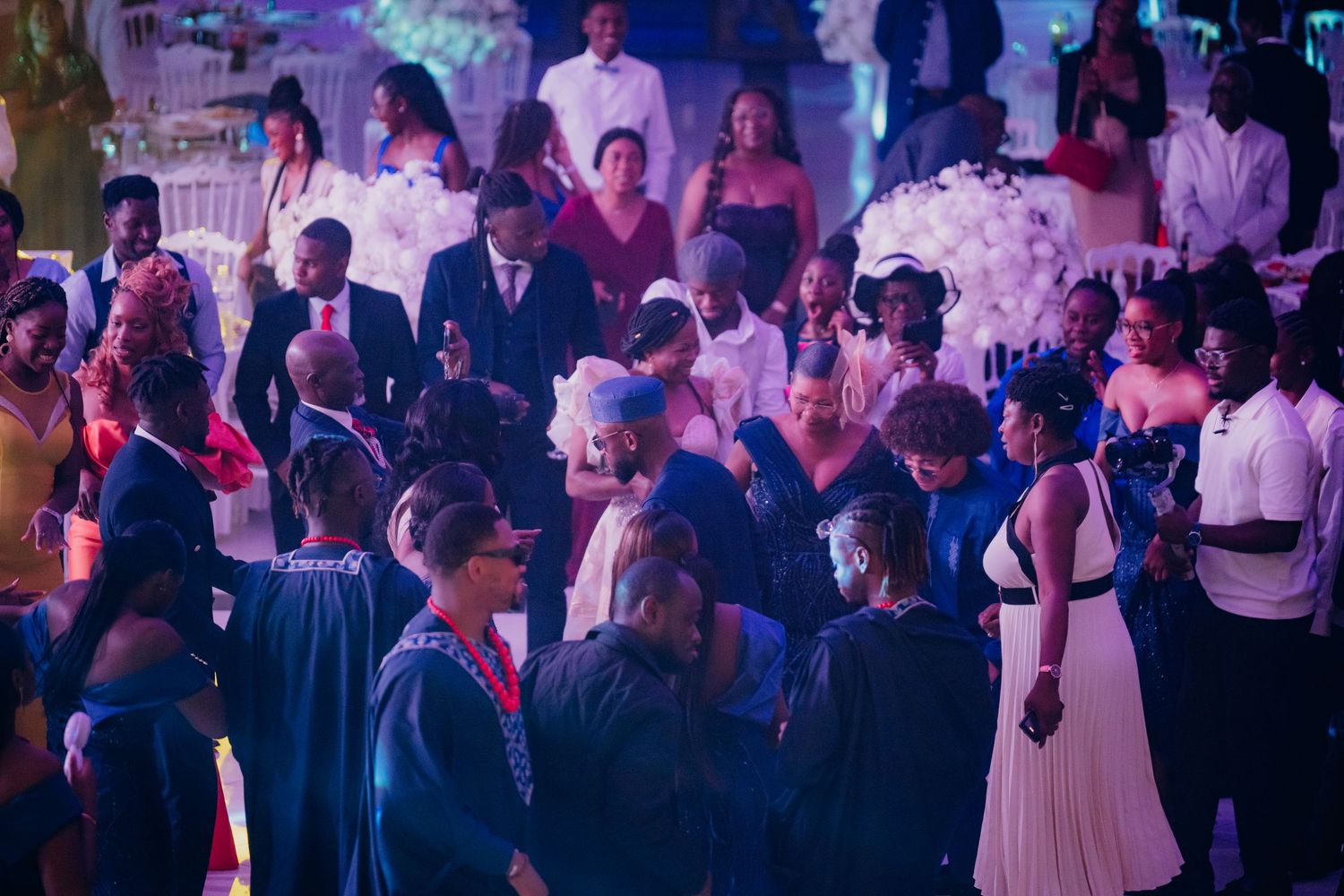 Wedding reception dance floor filled with guests enjoying the celebration under purple mood lighting.