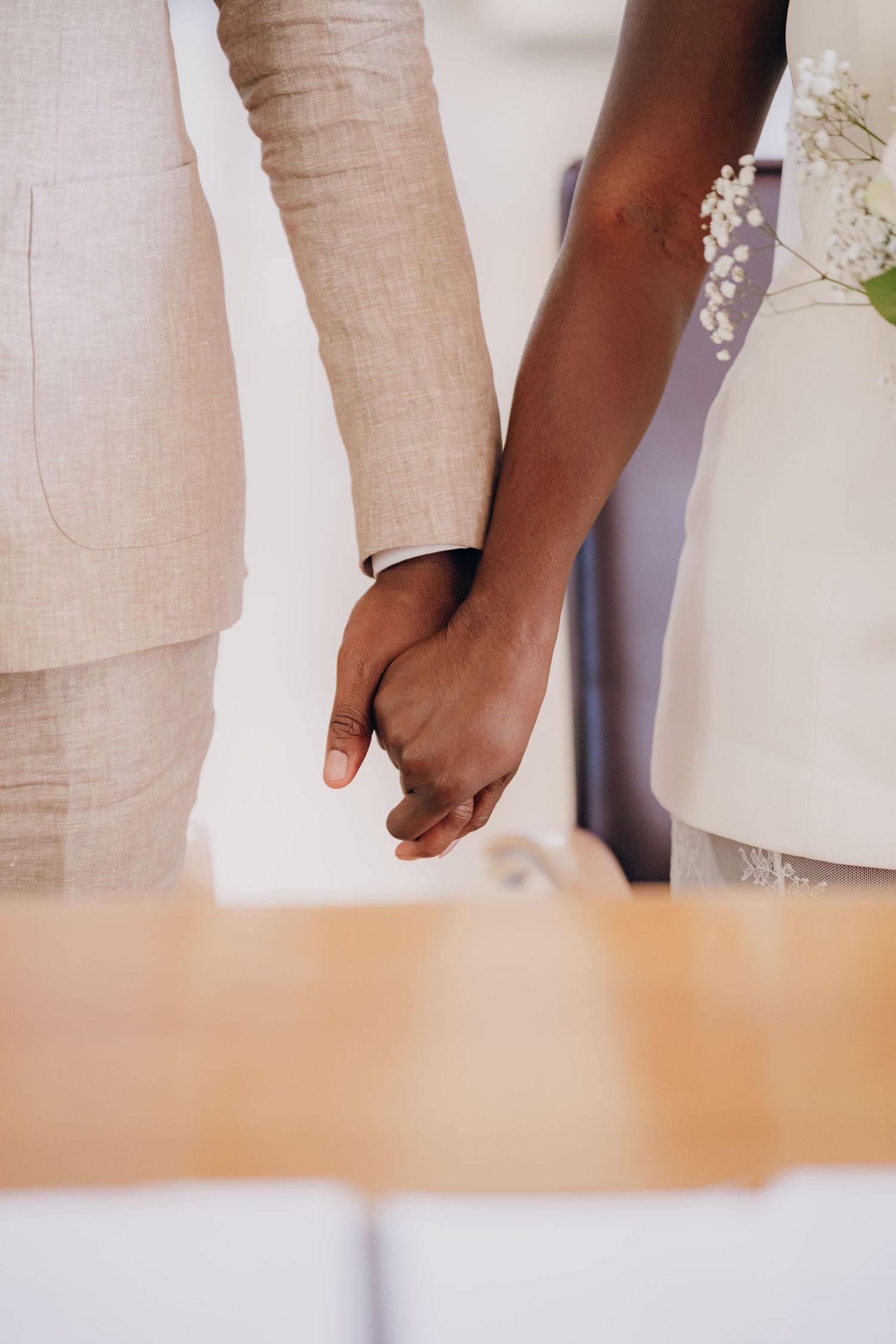 Close-up of hands holding white flowers during a wedding ceremony.