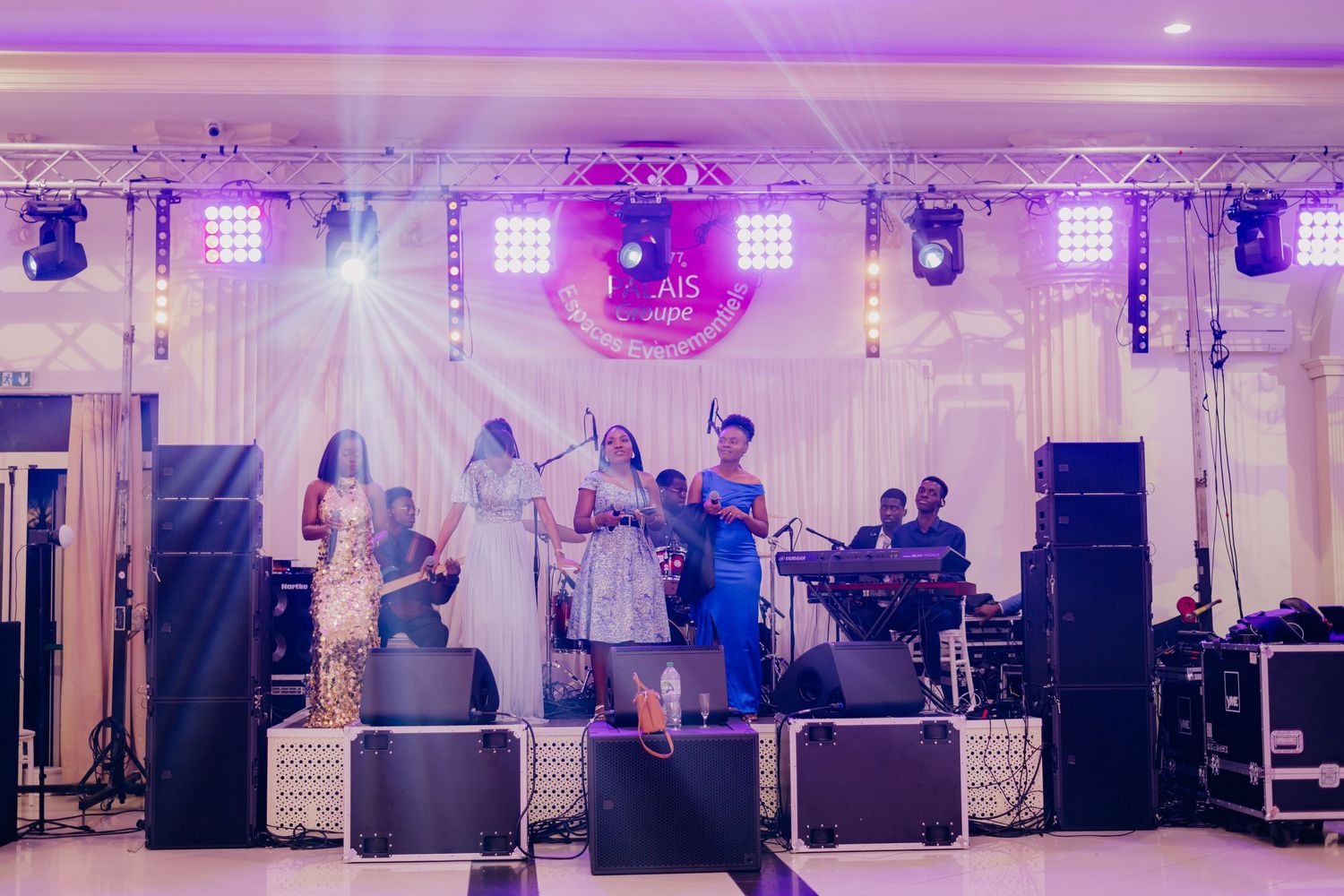 A large wedding reception venue with purple lighting, disco ball, and white drapes decorating the elegant ballroom space.