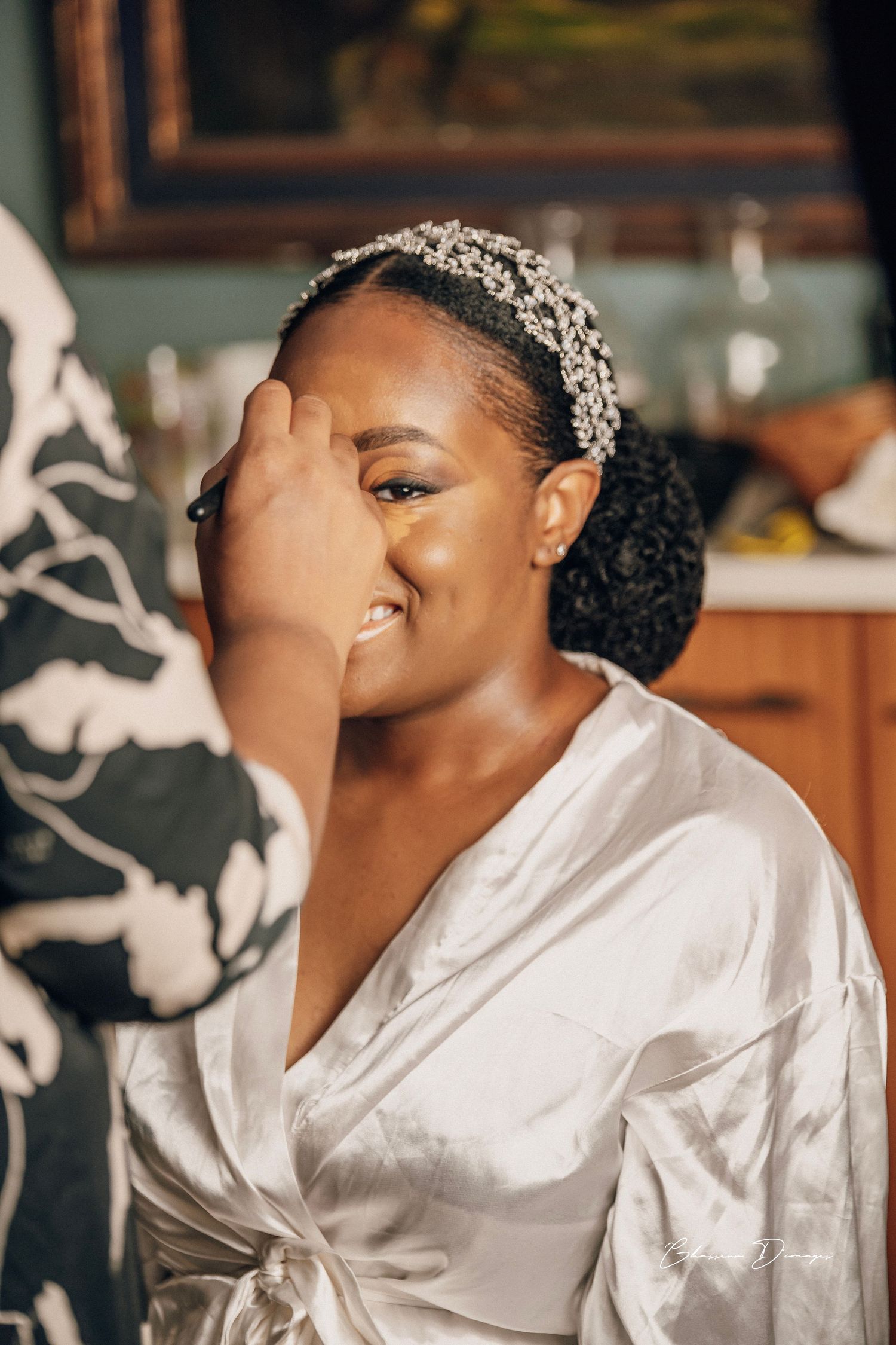 A candid wedding preparation moment showing a white silk robe and crystal headpiece in an elegant indoor setting.