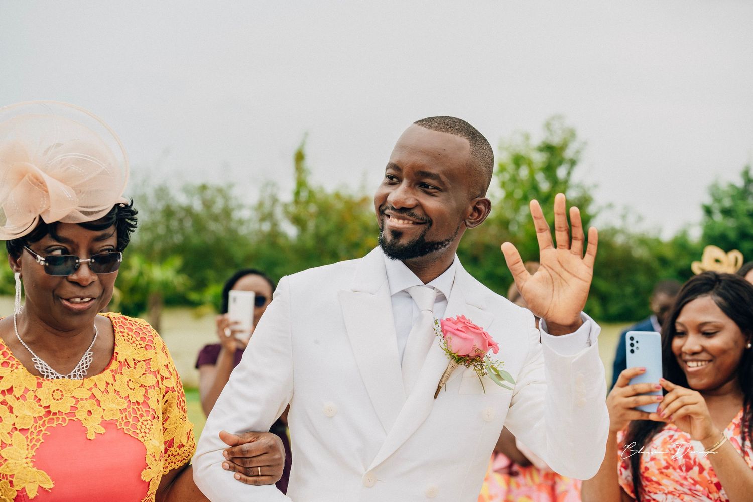 Guests in colorful attire celebrate joyfully at an outdoor wedding reception.