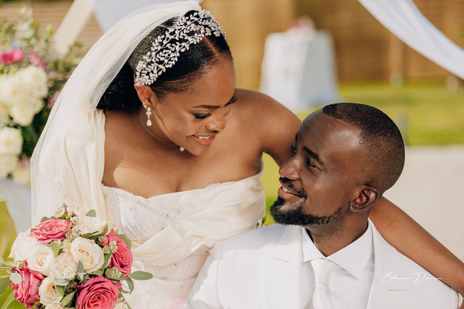 Intimate wedding portrait under decorated arch with pink rose bouquet.