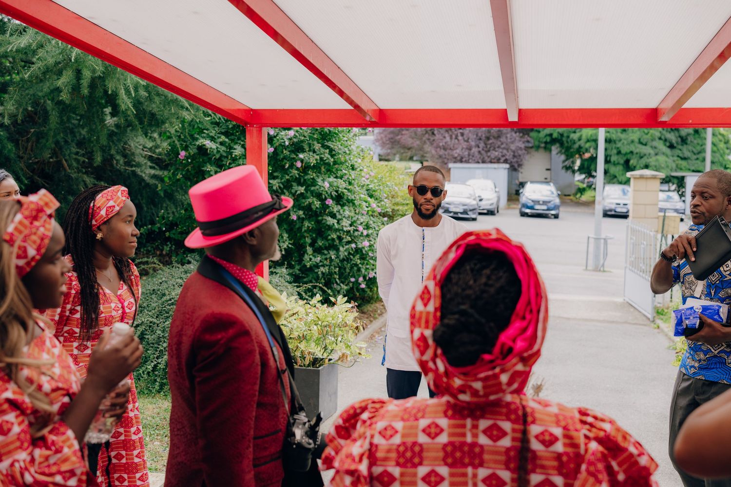 People in red and white attire gathered under a white canopy for an outdoor celebration.