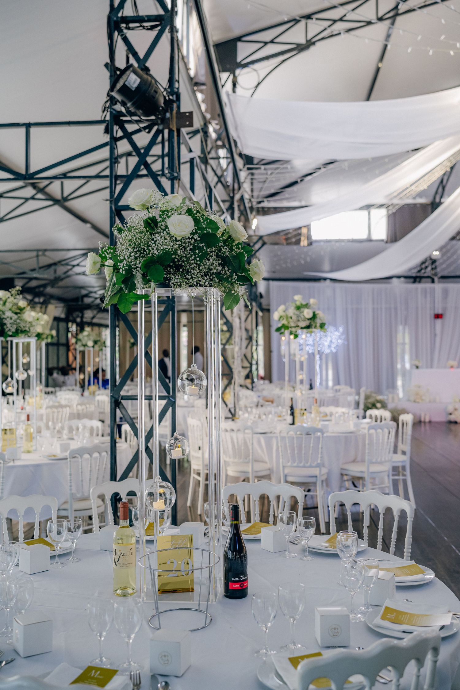 Elegant wedding reception venue with white draping, crystal chandeliers and formal table settings.