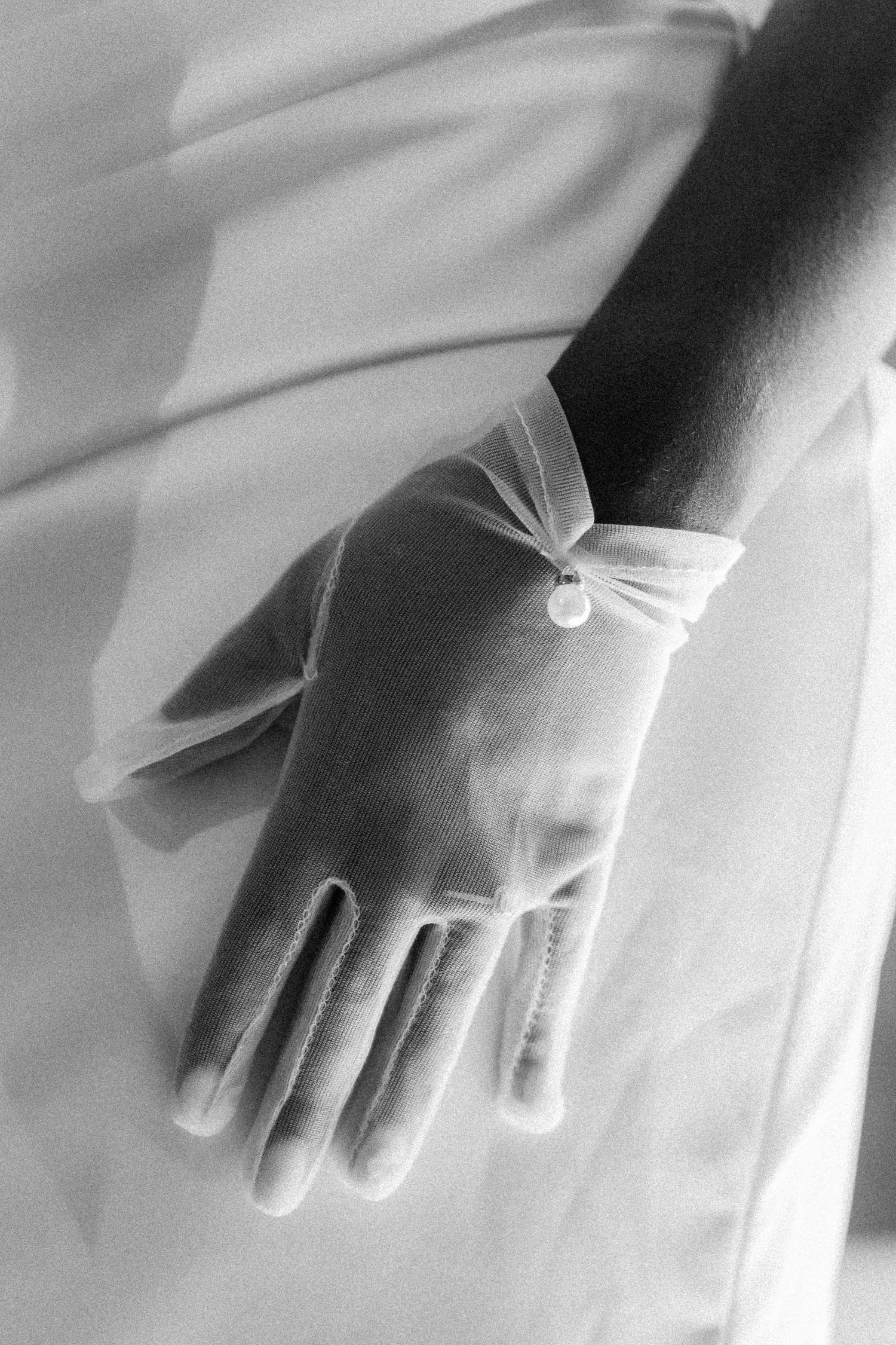 Close-up shots of hands wearing white gloves against a wedding dress.