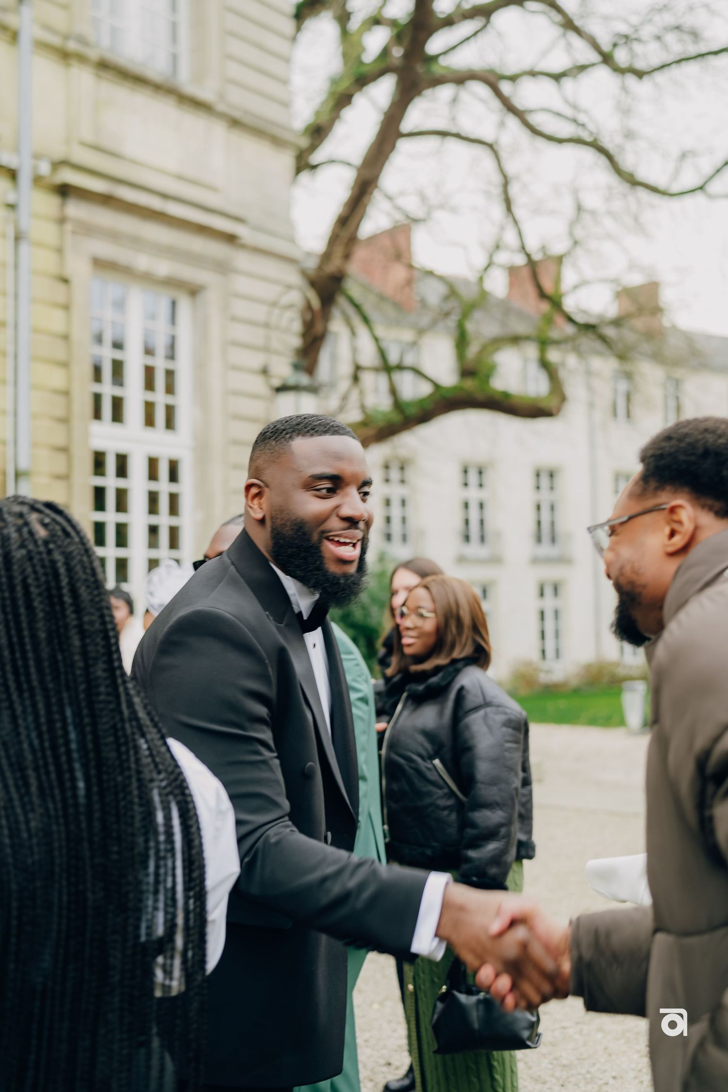 A formal gathering outside a historic building with people greeting each other.