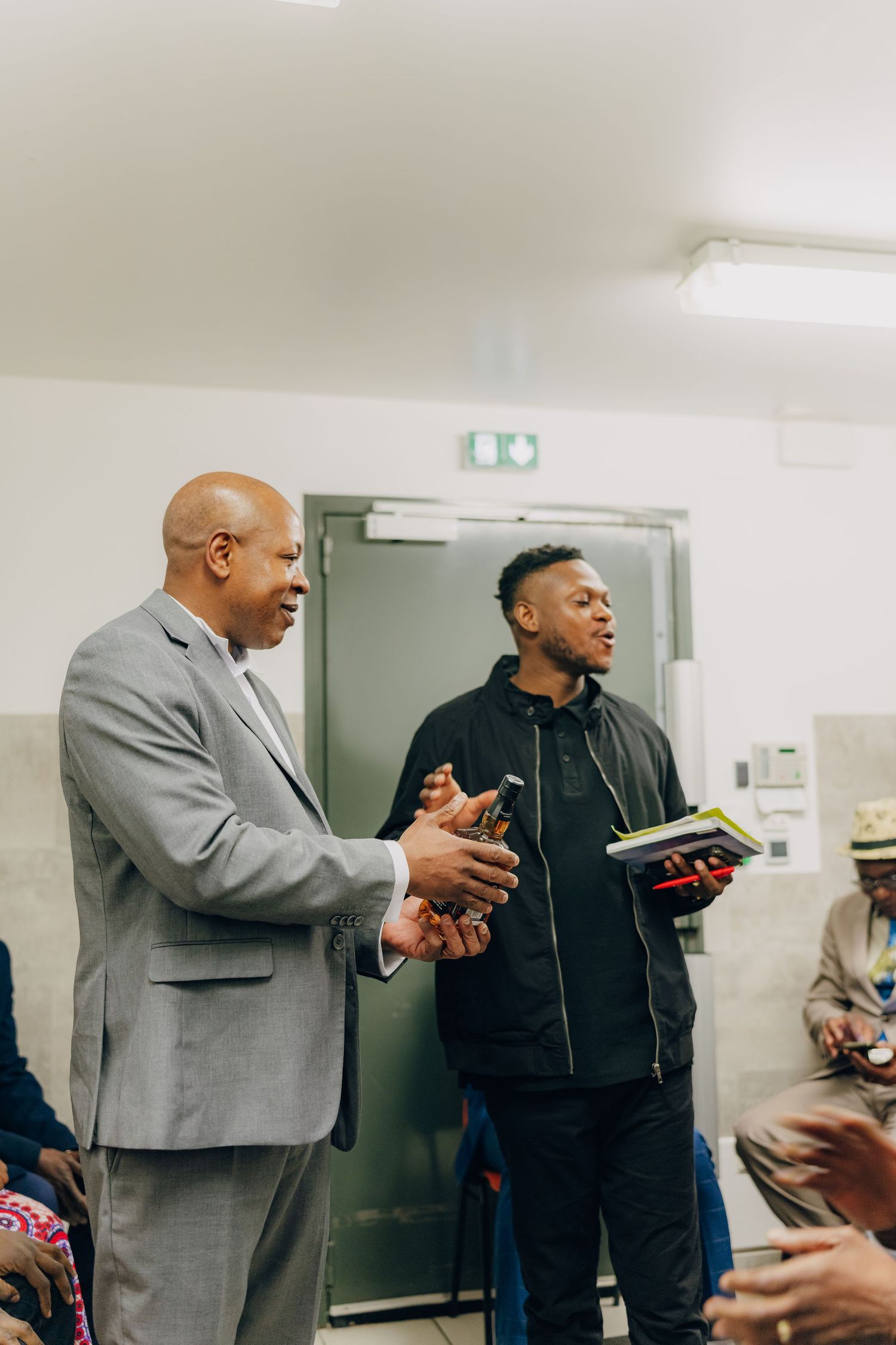 Two people having discussion standing in hallway with one holding box.
