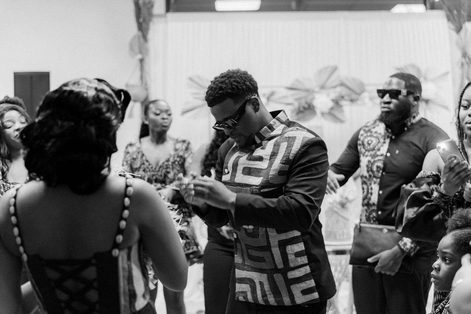 Black and white photo of guests mingling during a social gathering in an indoor venue.