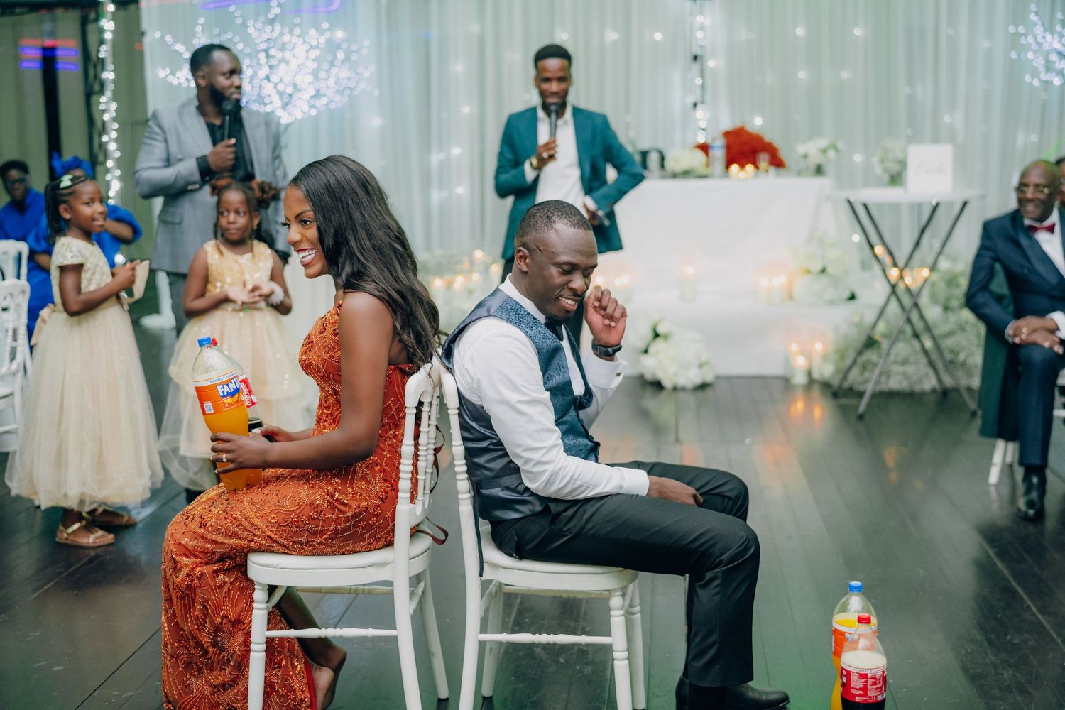 A romantic couple shares an intimate dance moment at a wedding reception with twinkling lights in the background.