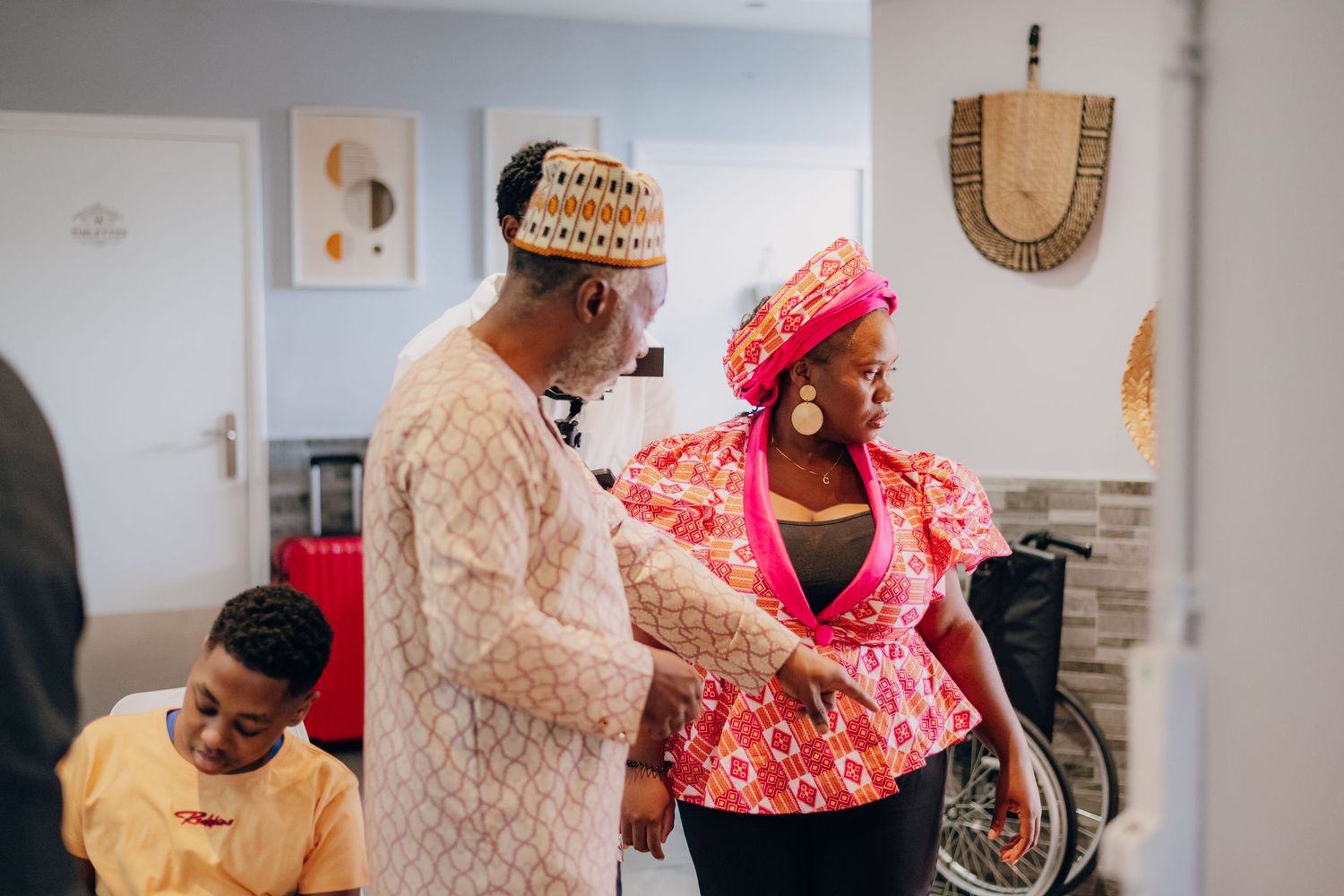 Festive gathering with colorful traditional African attire and decorative wall hangings in the background.