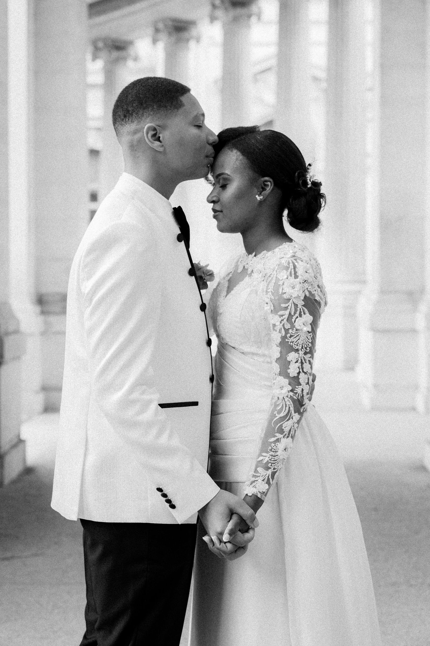 A black and white wedding photo series showing tender moments between newlyweds under elegant white columns.