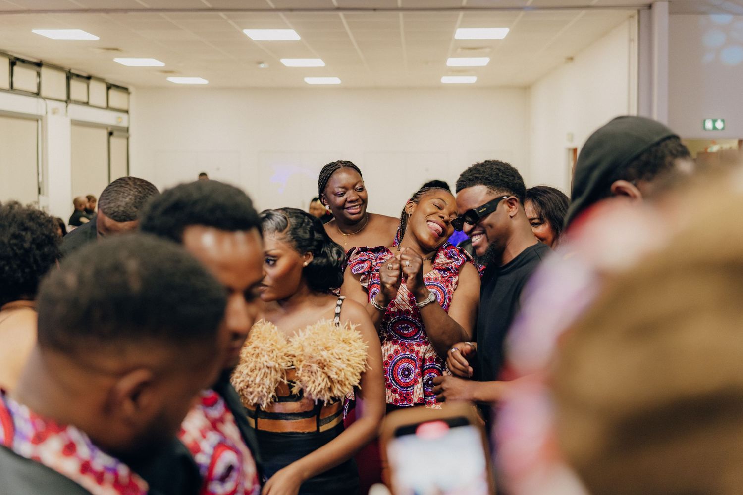 Crowd of party guests in formal attire gathering and socializing indoors.