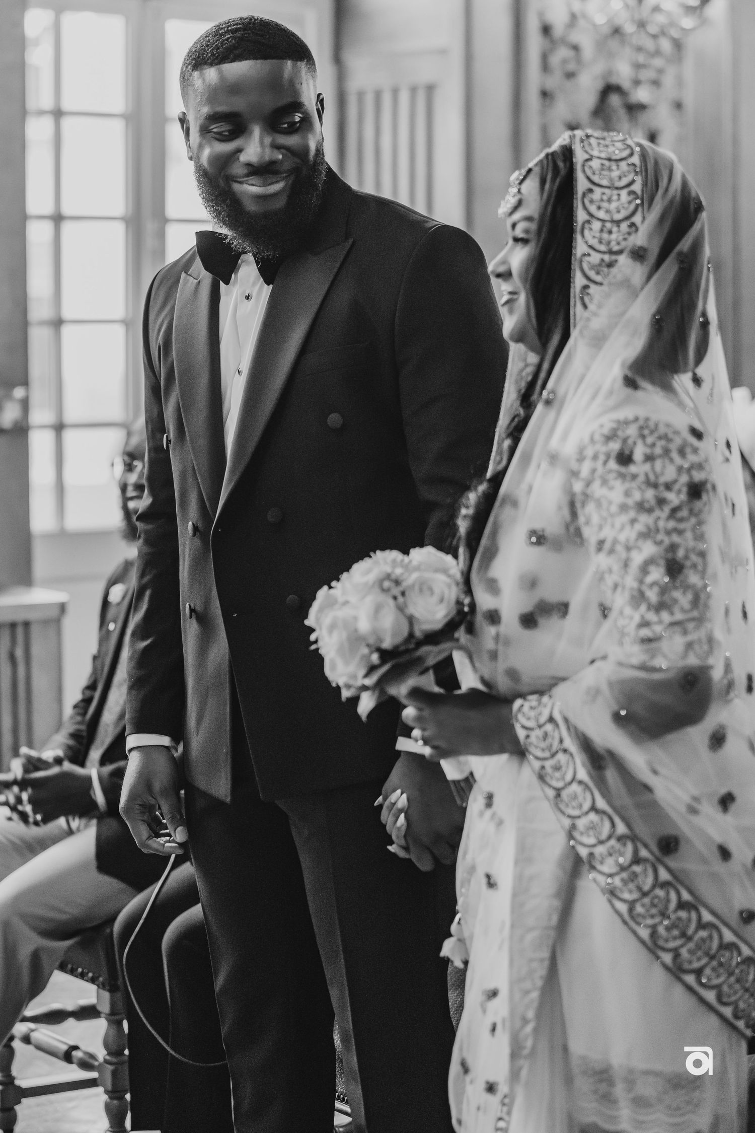 A candid wedding moment showing the couple smiling in traditional fusion formal attire.