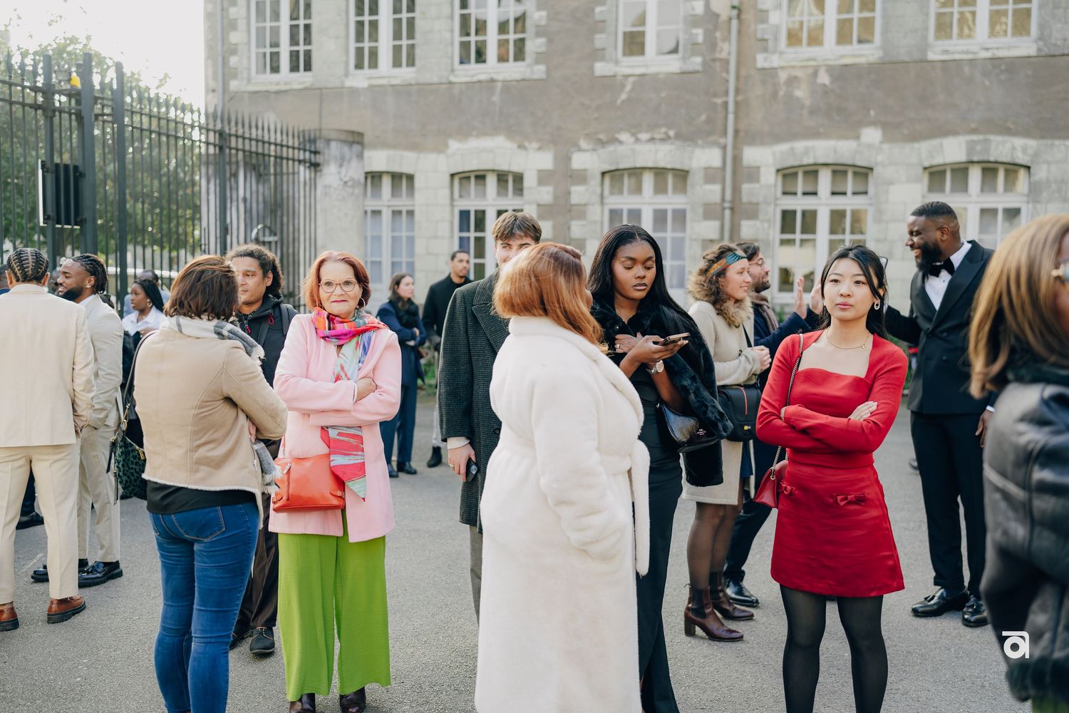 A diverse group of people gathered outside a building having casual conversations in a social setting.