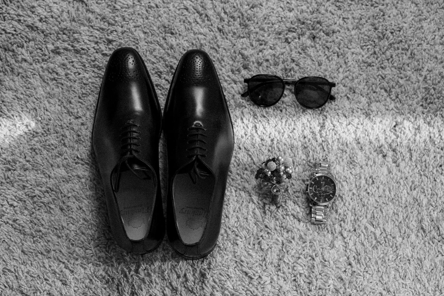A sequence of black dress shoes arranged in a row on a gray carpet showing different angles and perspectives.