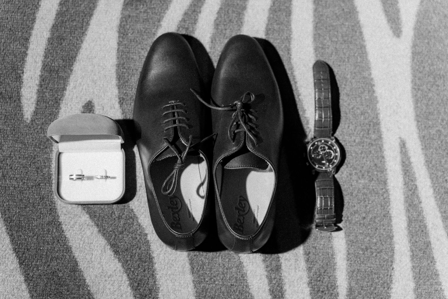 Row of black formal dress shoes displayed on a shelf against a gray background.