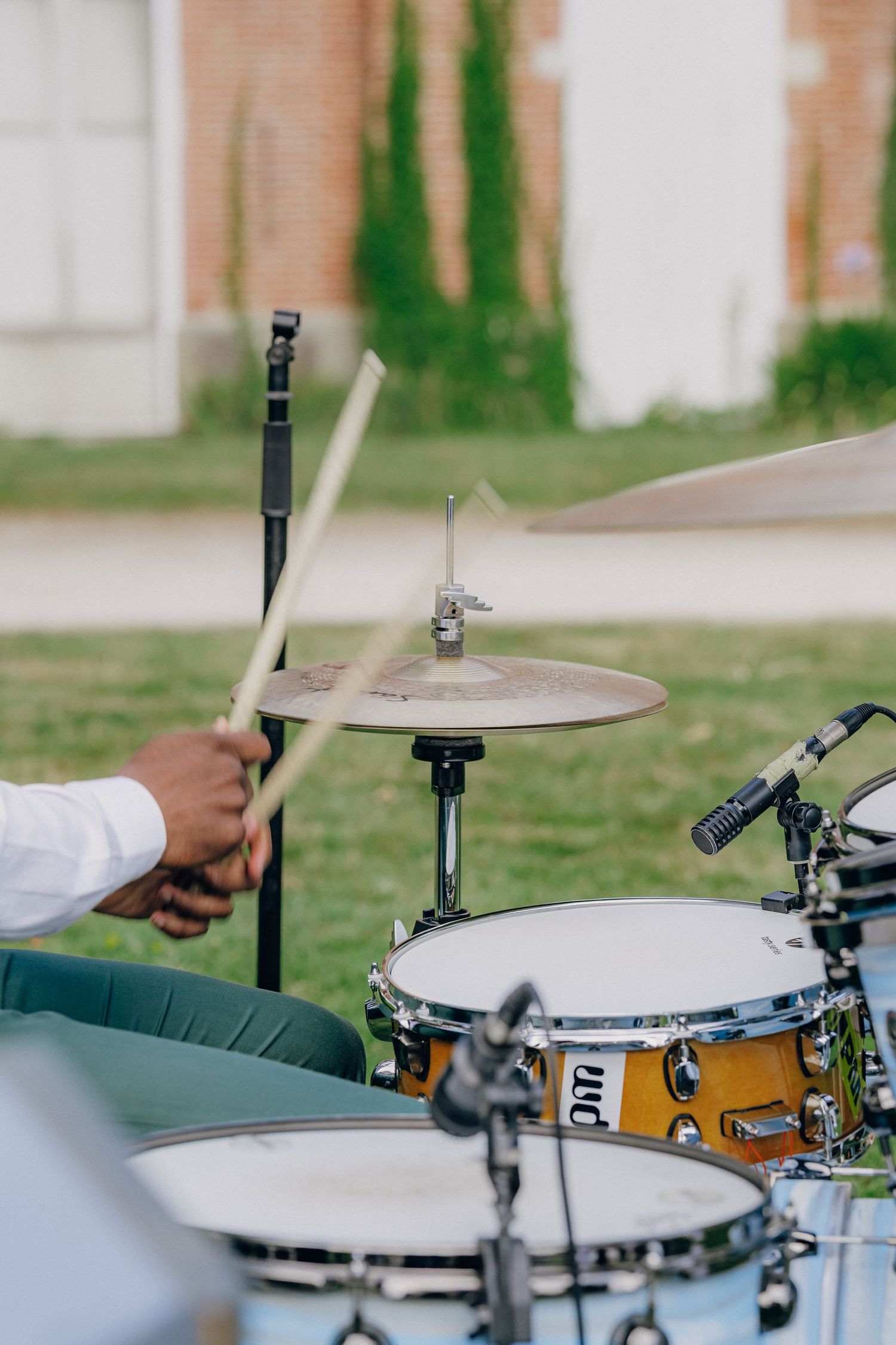 Professional drum kit setup with white cymbals and wooden drums at an outdoor event.
