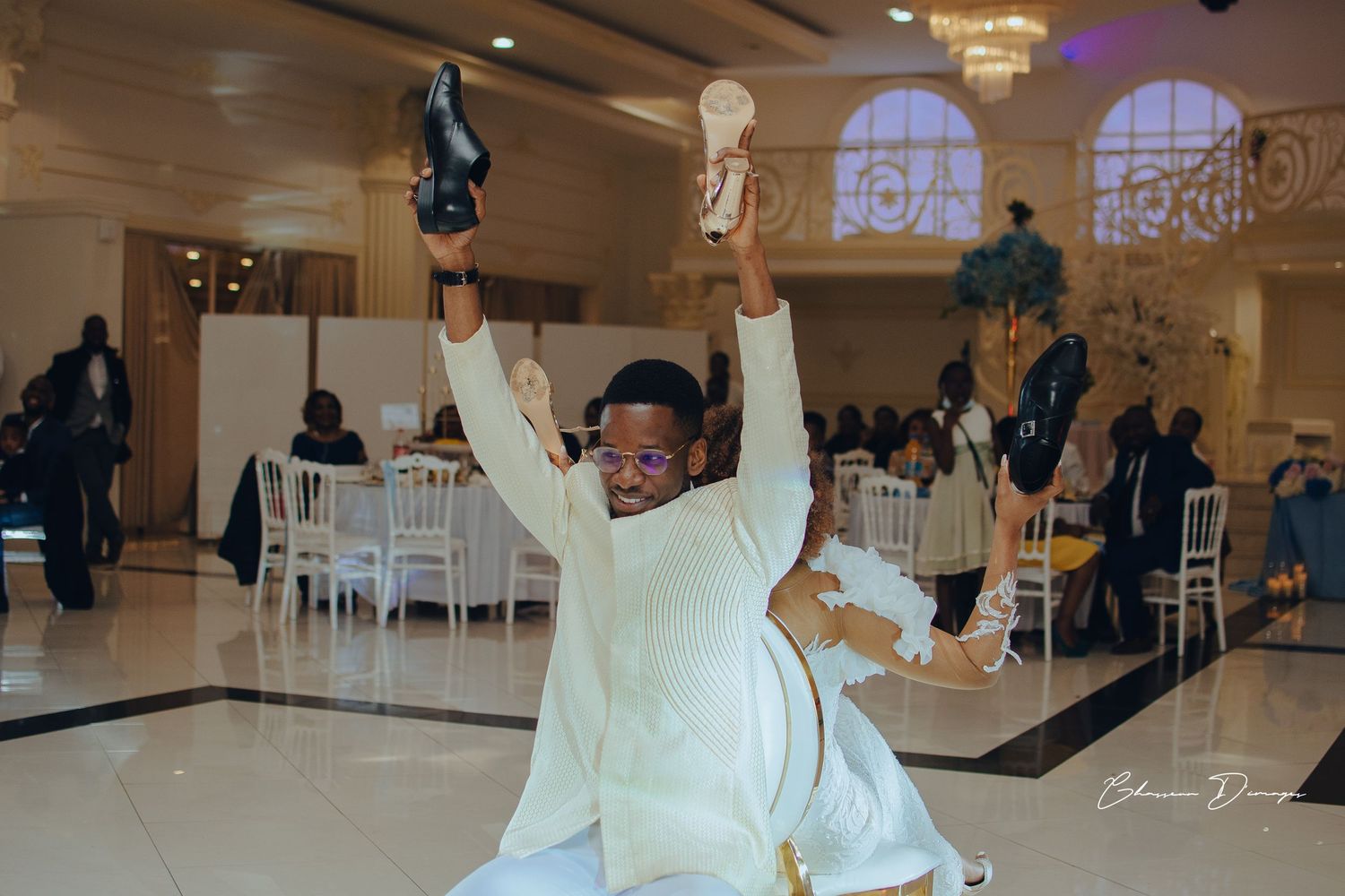 Energetic dance moves on white ballroom floor during wedding reception celebration.