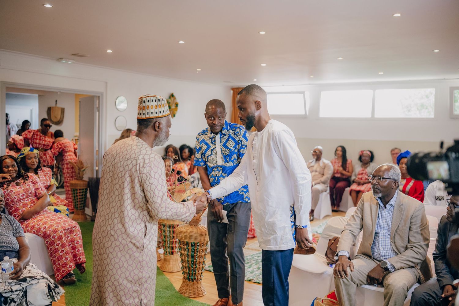 Traditional African wedding reception with guests in vibrant attire gathered in a modern indoor venue.