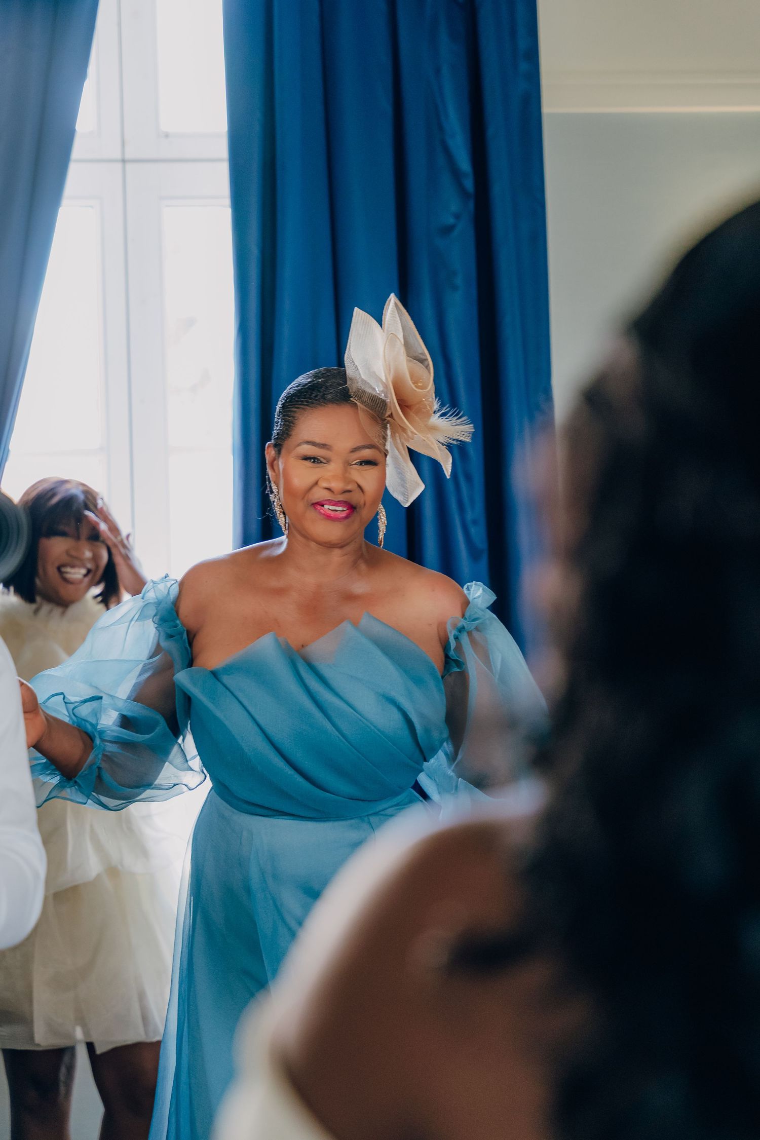 A bridesmaid in a turquoise blue gown smiles during wedding preparations.