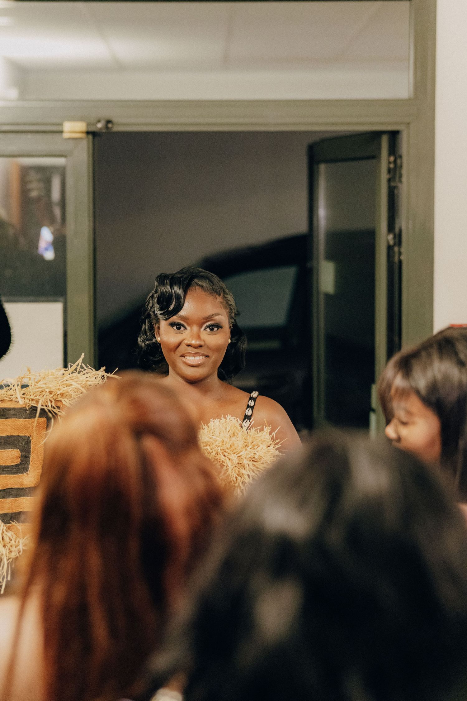 A guest wearing a golden feathered dress amongst a crowd at an indoor celebration.