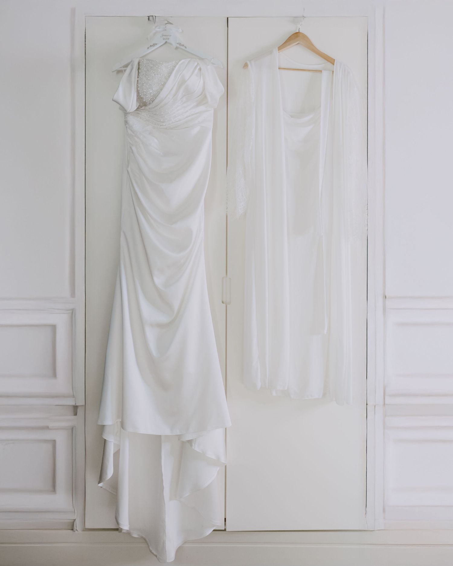 White wedding dress hanging on wardrobe doors in a minimalist setting.