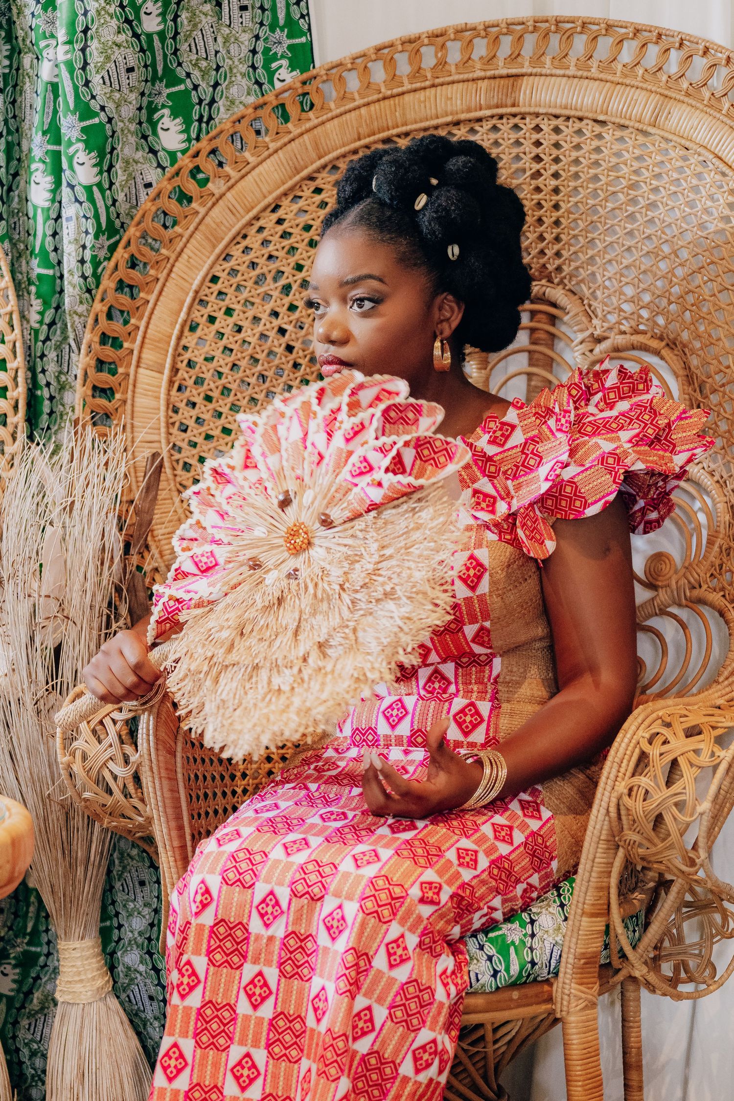 Decorative scene with wicker peacock chair and pink floral patterns against natural backdrop.