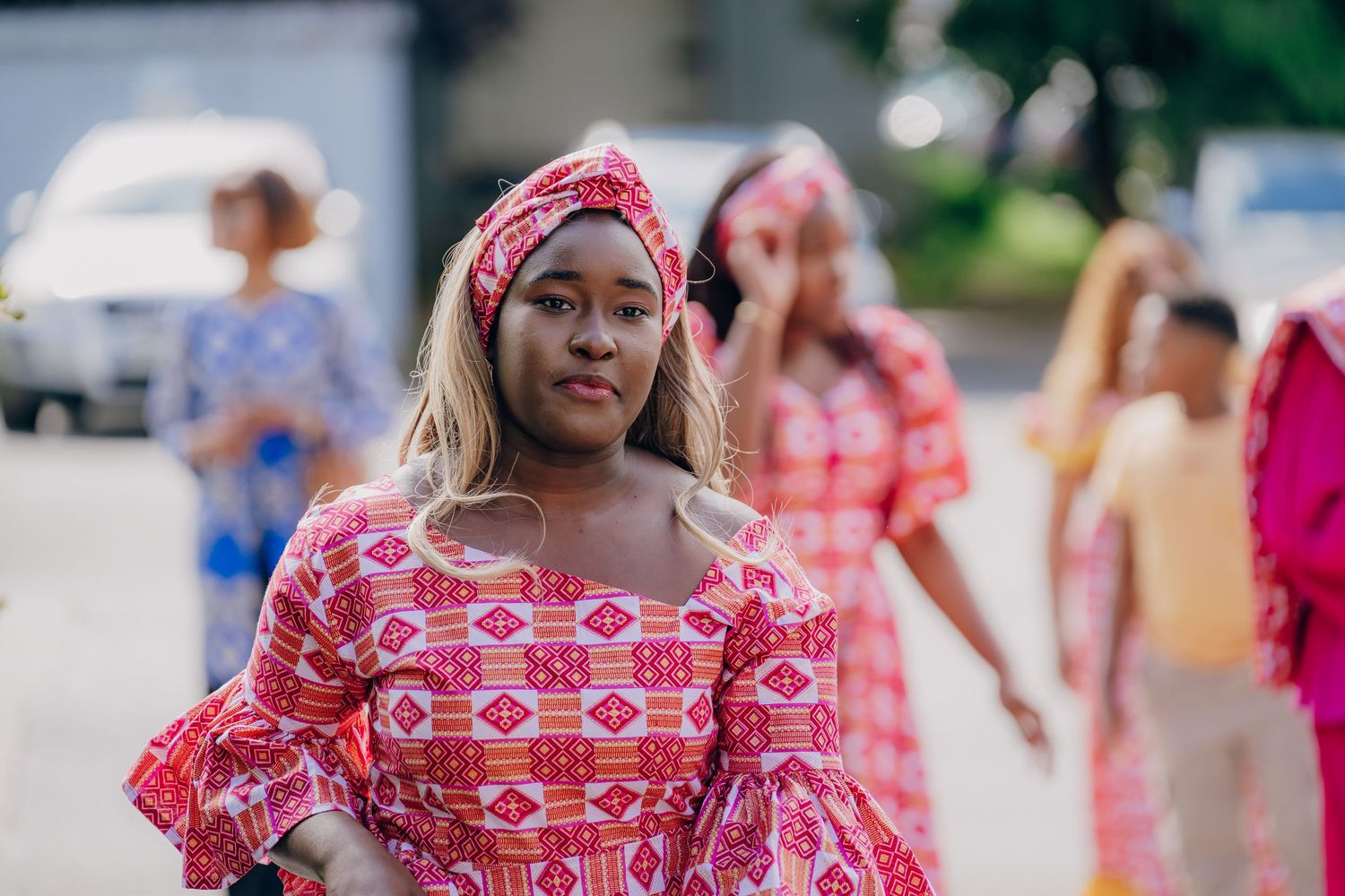 Vibrant pink and white patterned dress with ruffled sleeves at an outdoor celebration.