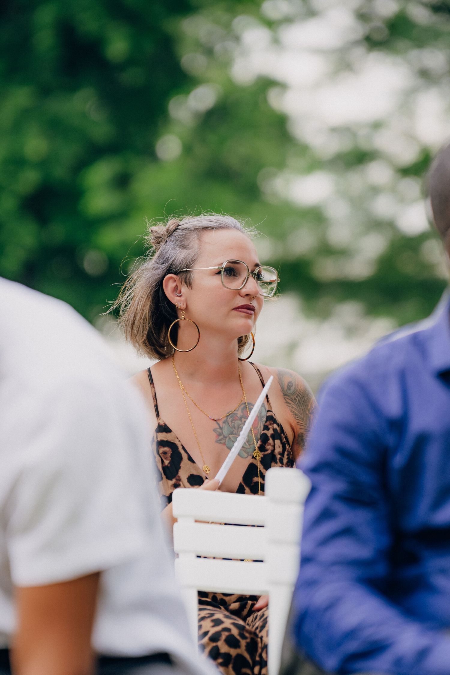 A sequence of candid outdoor shots showing someone in glasses and a leopard print top enjoying a drink at a gathering.