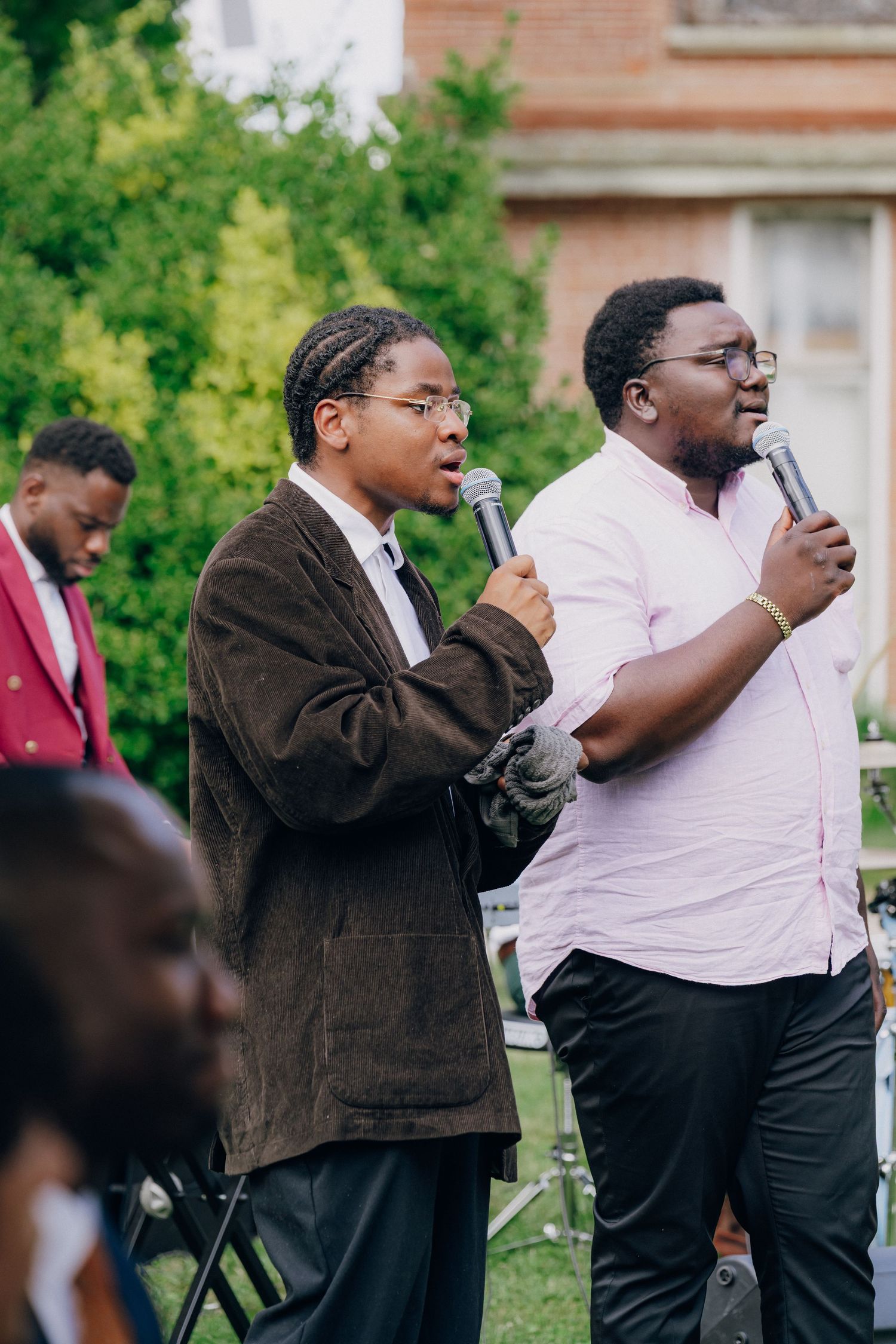 Wedding guests take photos on their phones during an outdoor ceremony.