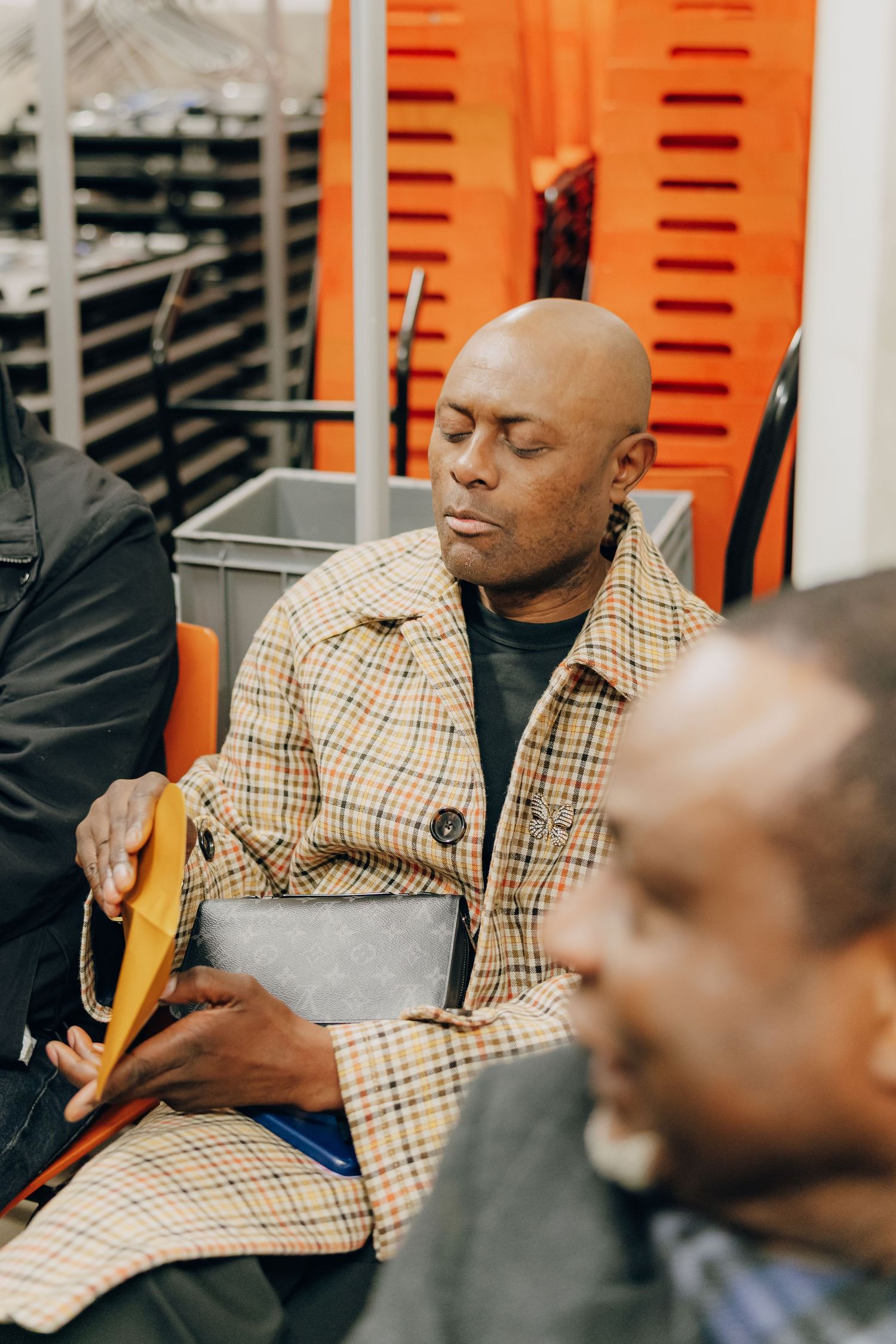 Someone rests in a plaid jacket while sitting on public transit.