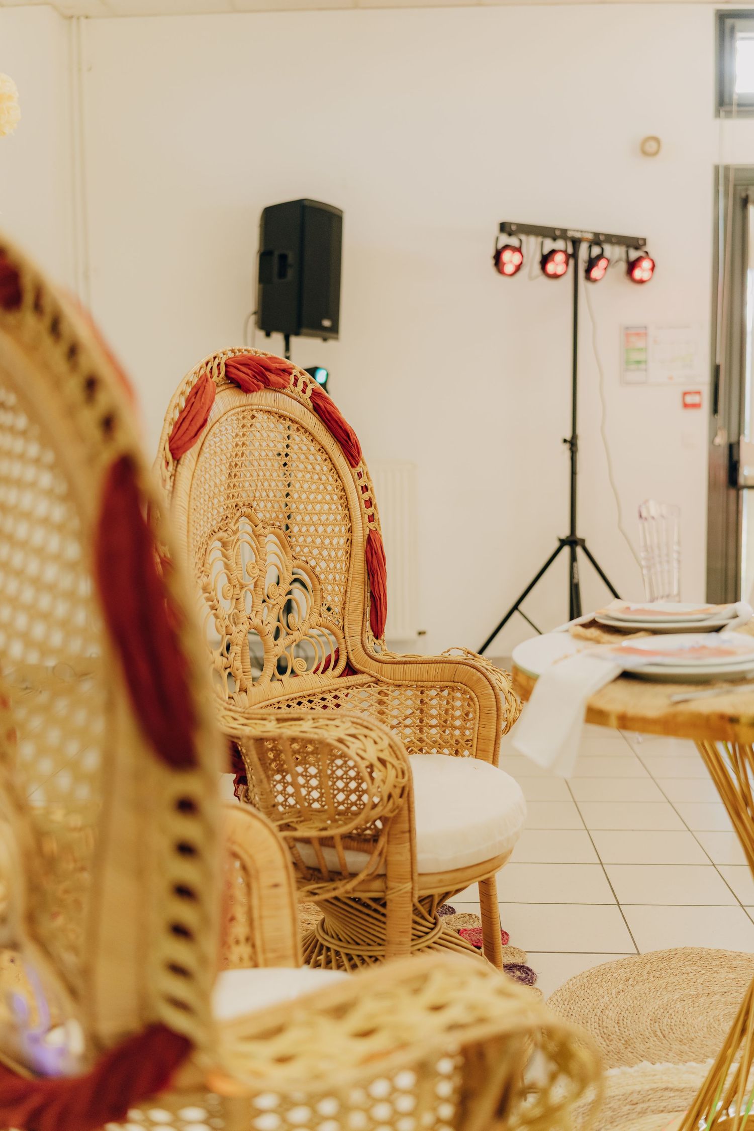 Ornate wicker peacock chair with white cushions and stage lighting equipment in the background.