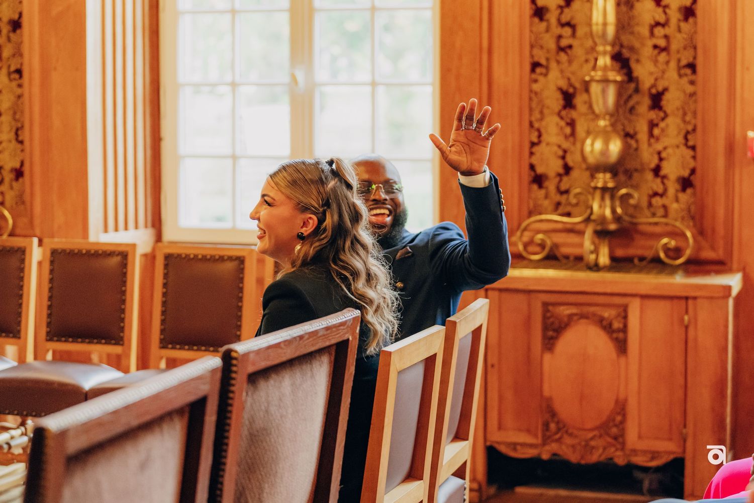 Attendees celebrating with raised hands in an elegant wood-paneled room with ornate decor.