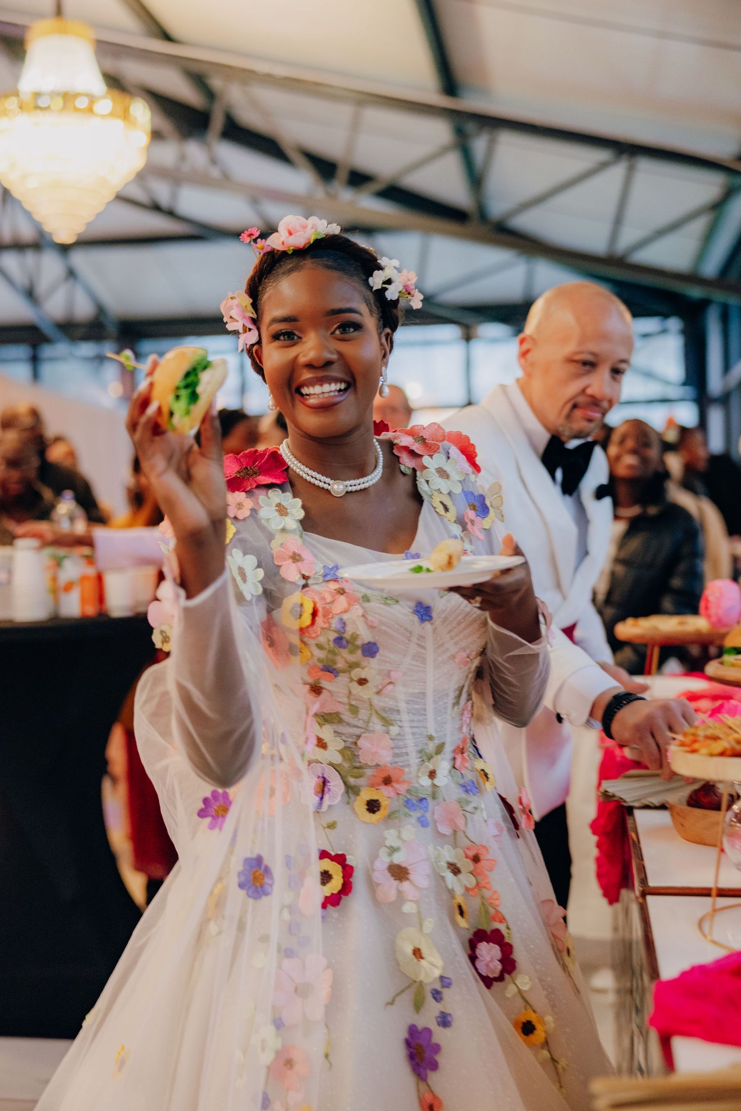 A joyful celebration with people in white attire dancing and having fun under a white tent at an outdoor event.