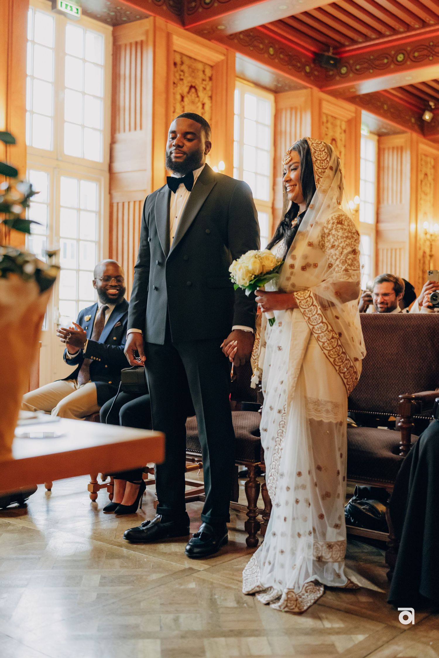 Couple stands in ornate wood-paneled room during wedding ceremony.