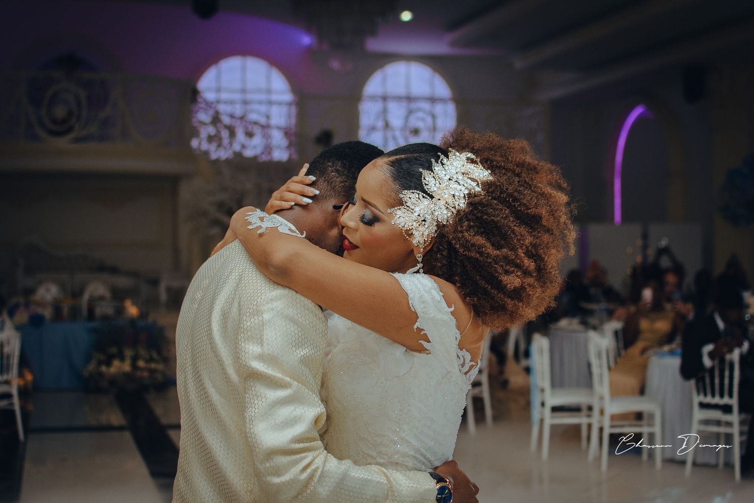 Intimate dance moment captured in dimly lit ballroom with decorative arches.