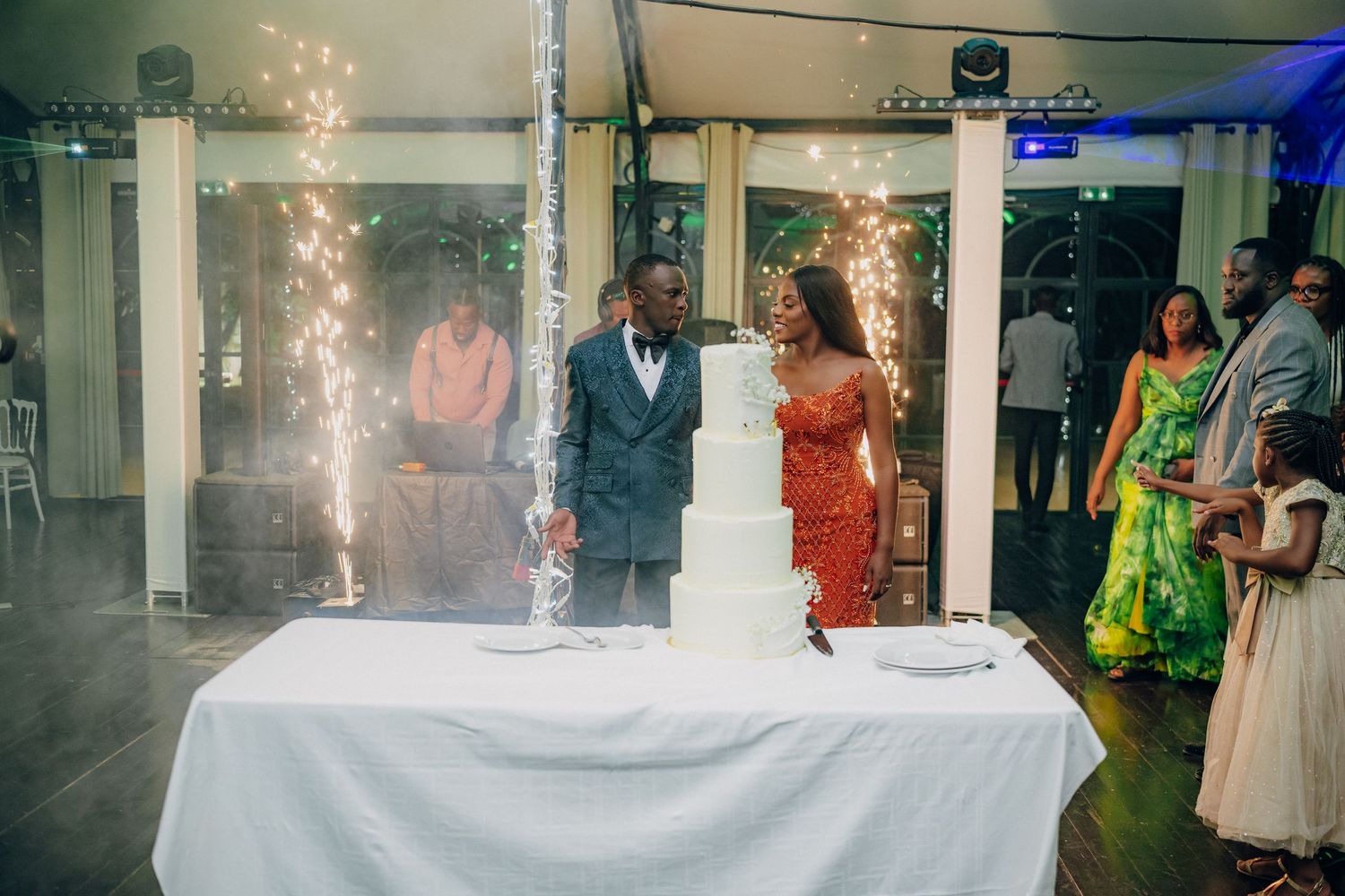 Wedding celebration with sparkler effects and guests in formal attire.