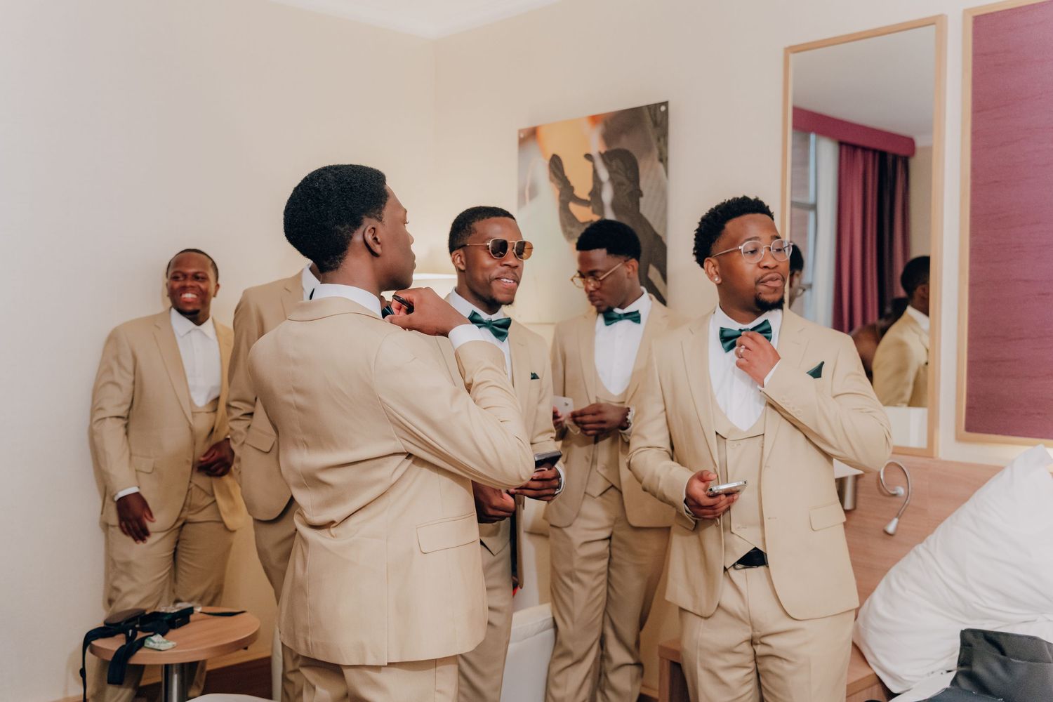 Groomsmen in beige suits and sunglasses pose together during a wedding celebration.
