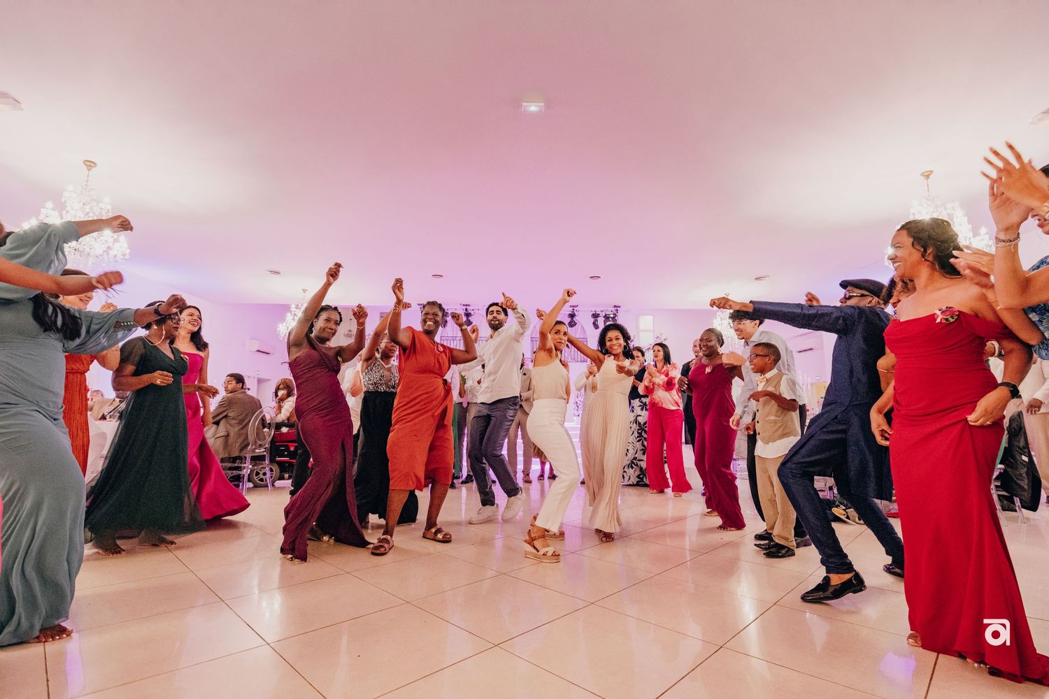 Wedding guests dancing and celebrating on the dance floor at a reception with colorful dresses and joyful energy.