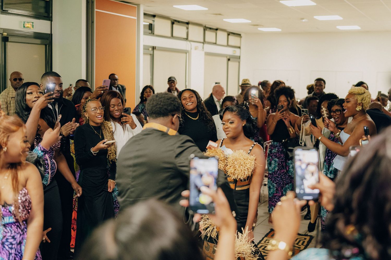 A crowded room full of people holding phones to capture a special moment at what appears to be a celebratory event.