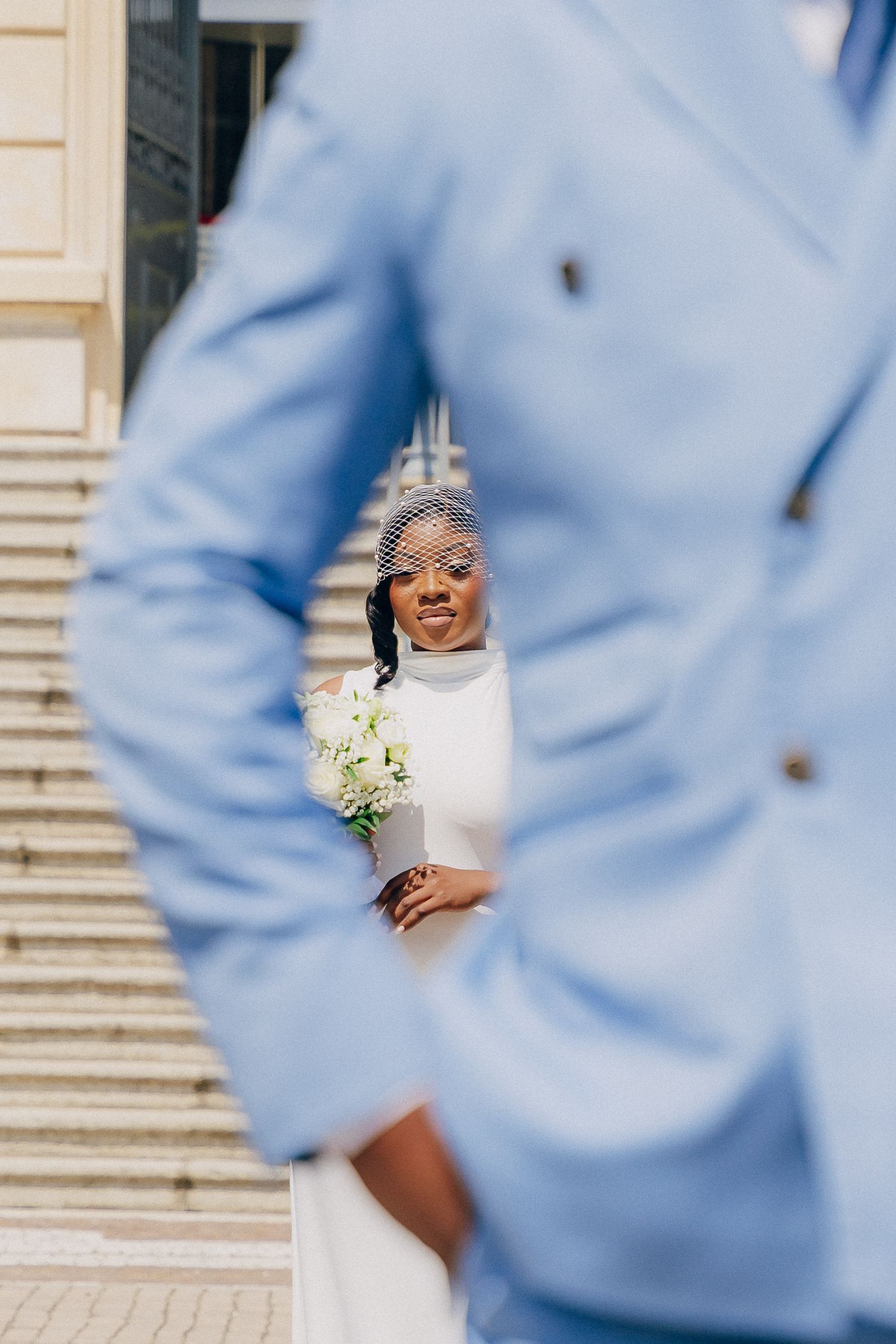 A joyful bride in a white wedding dress holds a bouquet while surrounded by light blue attire in an elegant setting.