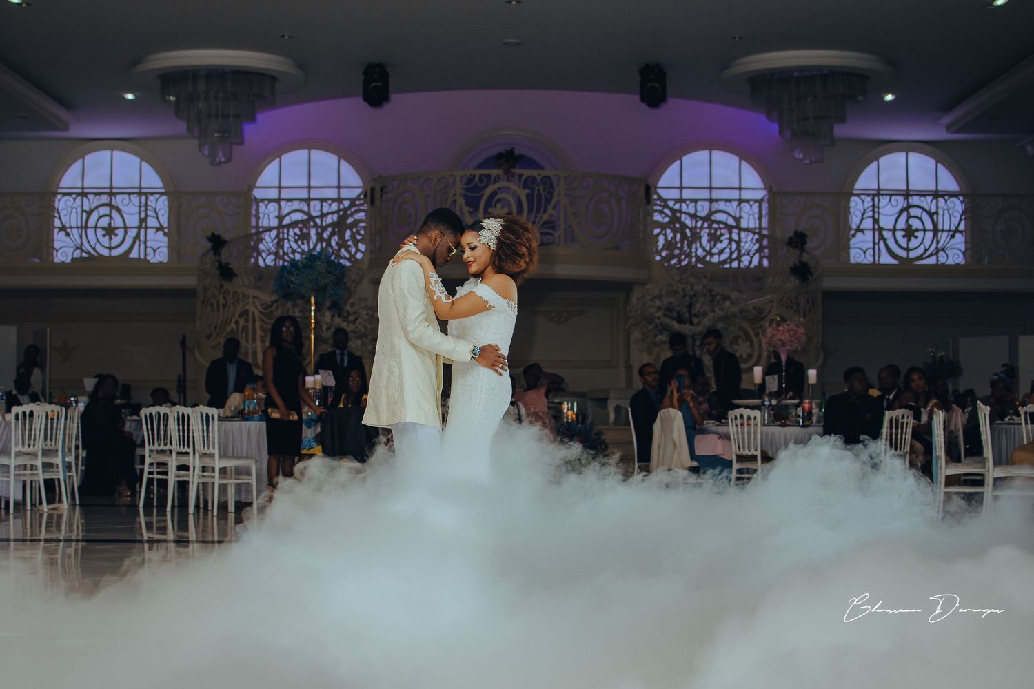 Romantic first dance with fog effects in elegant ballroom setting.