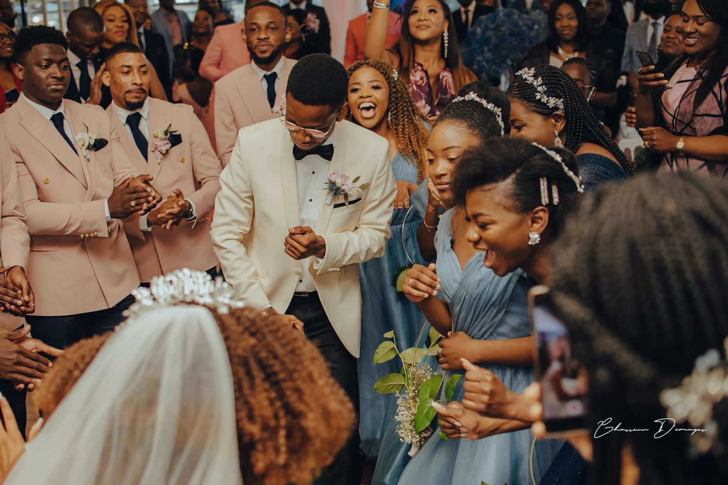 Wedding celebration with guests in pastel suits gathering around the couple during the ceremony.
