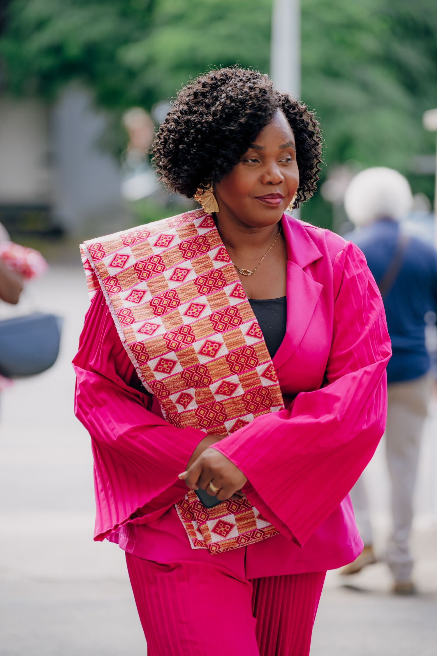 A vibrant hot pink blazer and patterned dress combination styled with elegant hand fan accessories.