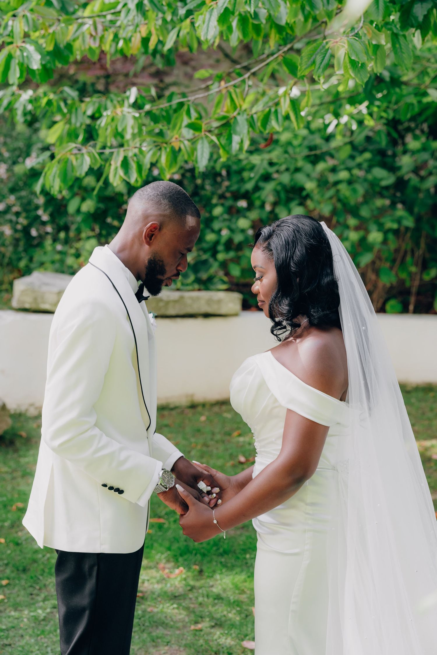 A wedding couple in white attire sharing intimate moments in a garden setting.