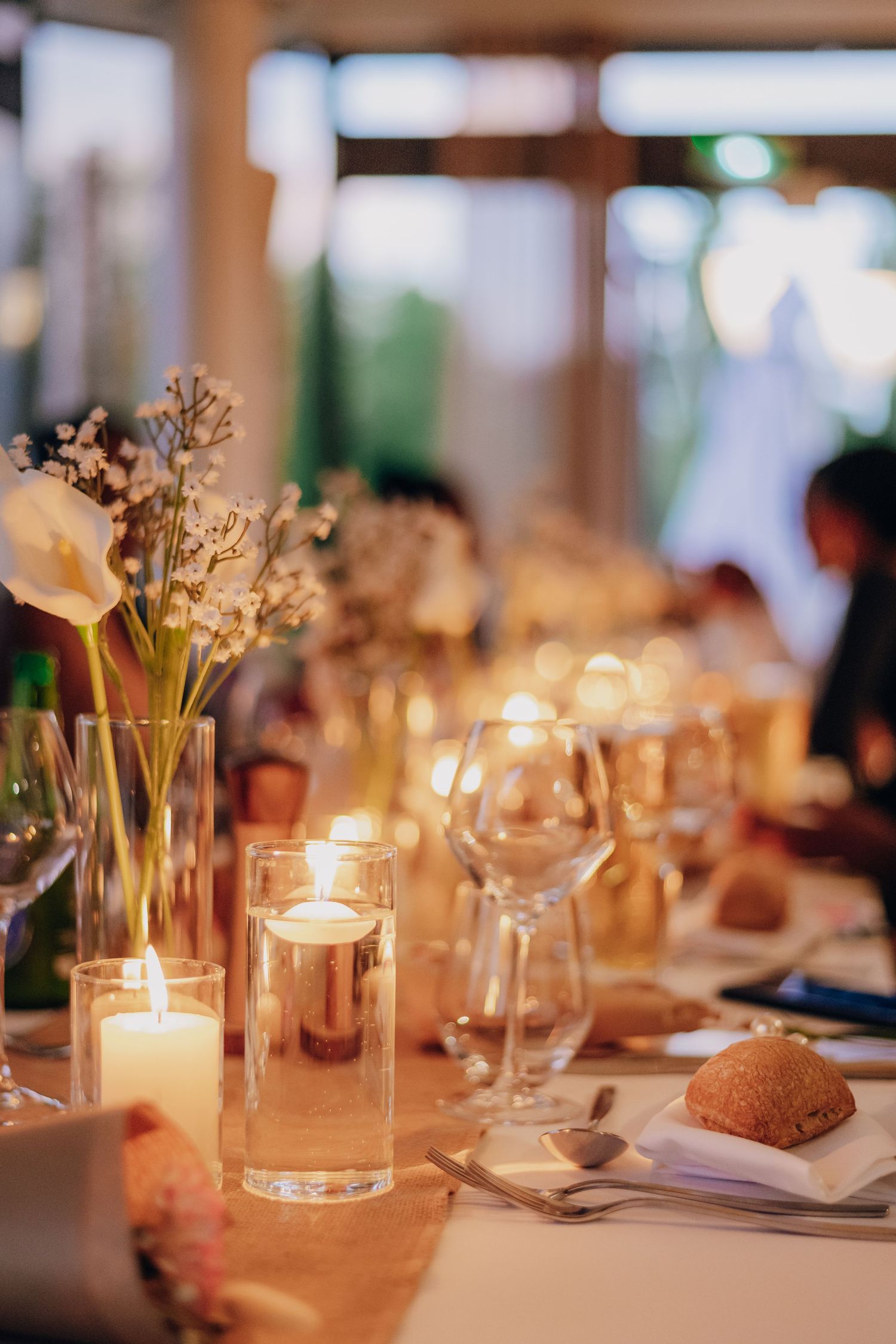 Elegant wedding reception table settings with glowing candles and delicate floral centerpieces create a romantic ambiance.