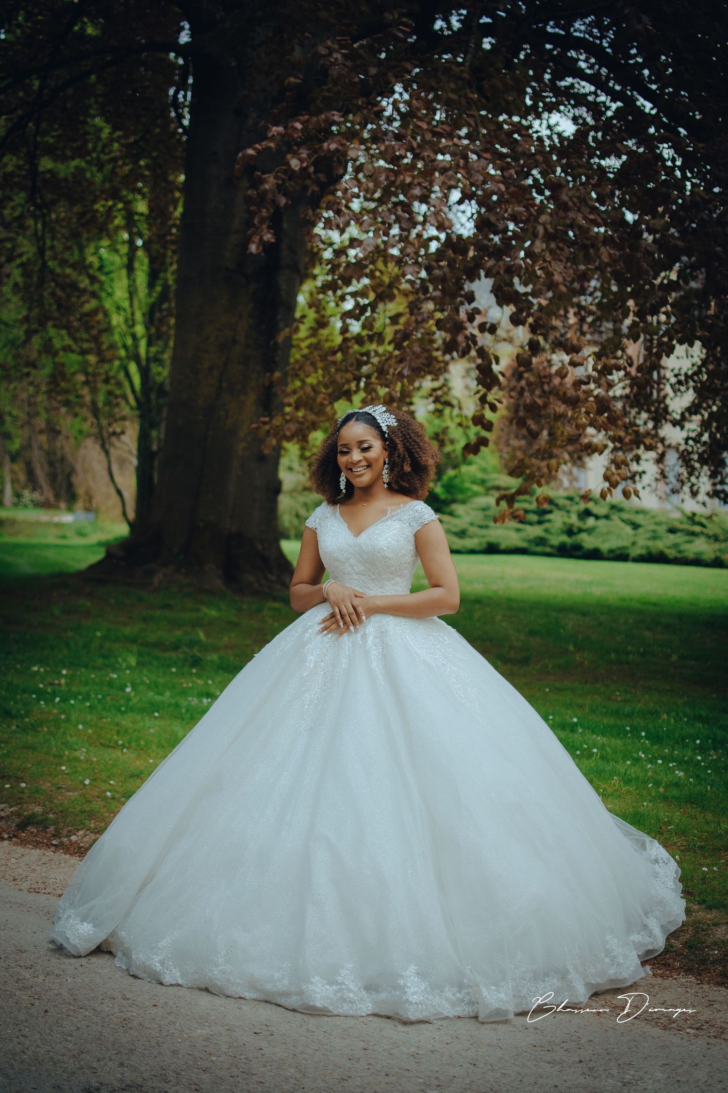 A stunning white ballgown wedding dress with cap sleeves photographed in a lush garden setting.