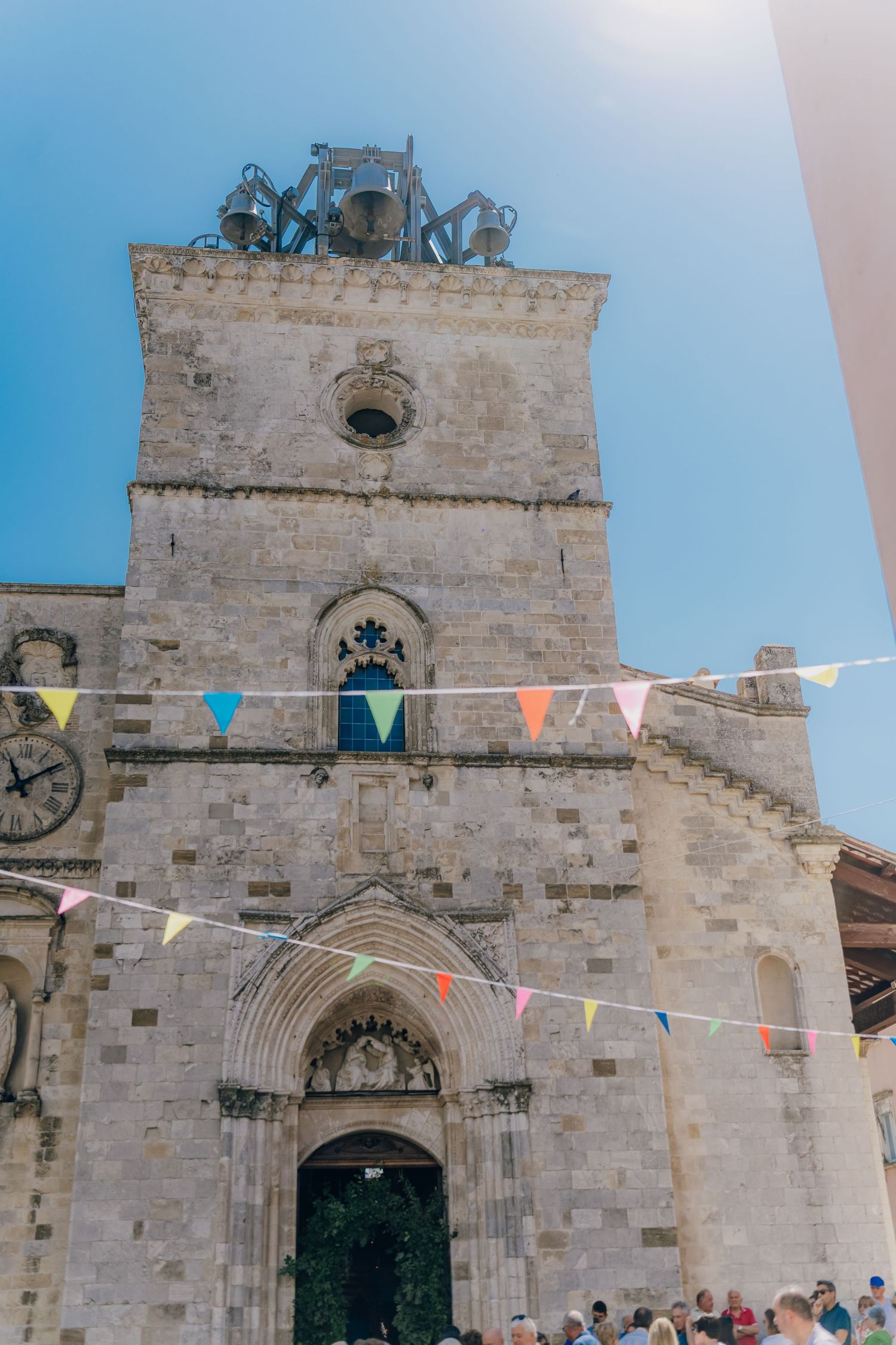 Historic stone church facade with colorful bunting flags against blue sky in medieval Spanish architectural style.